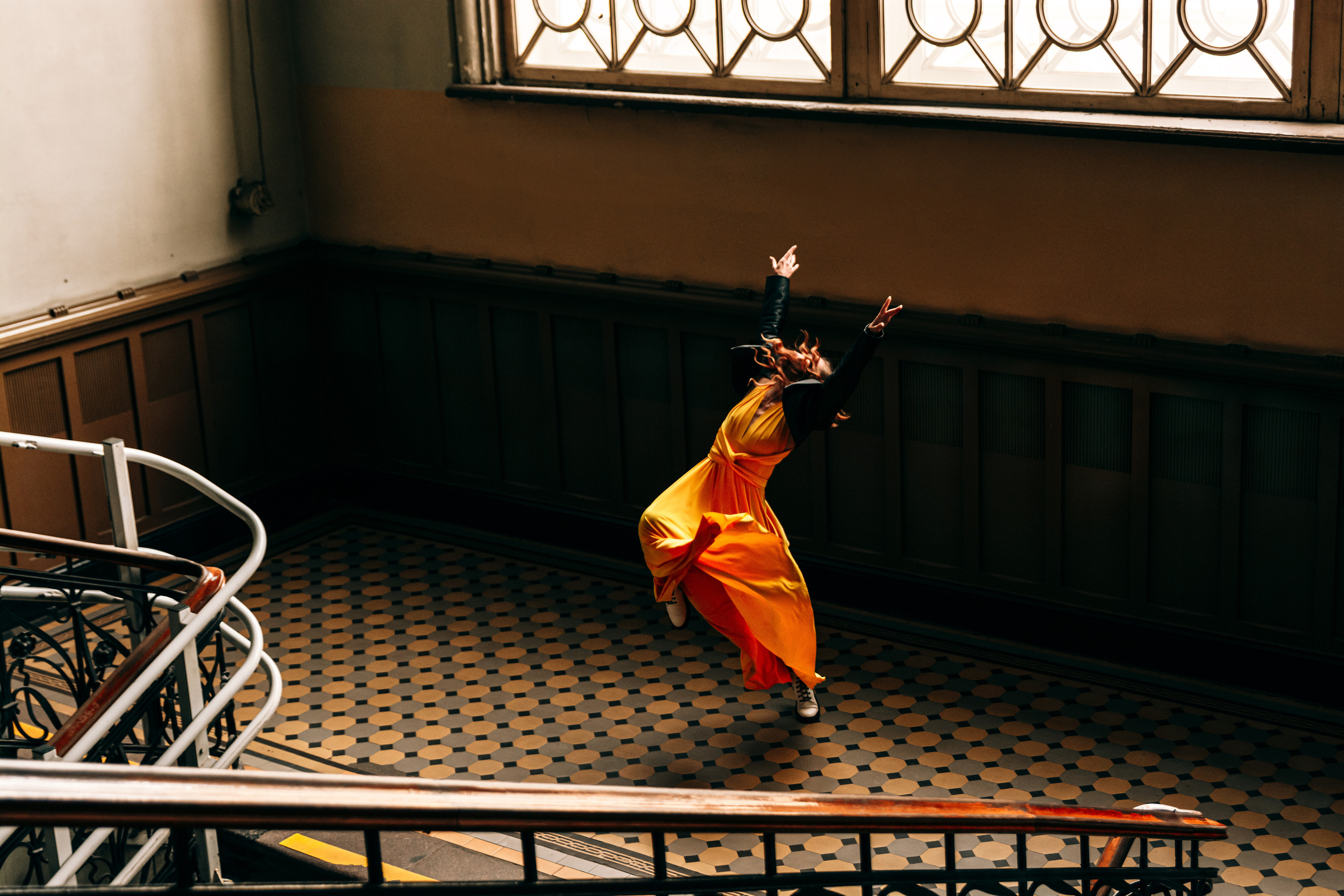 Эффектная девушка, одетая в огненное желтое платье, танцует на Витебском вокзале, привлекая взгляды прохожих.