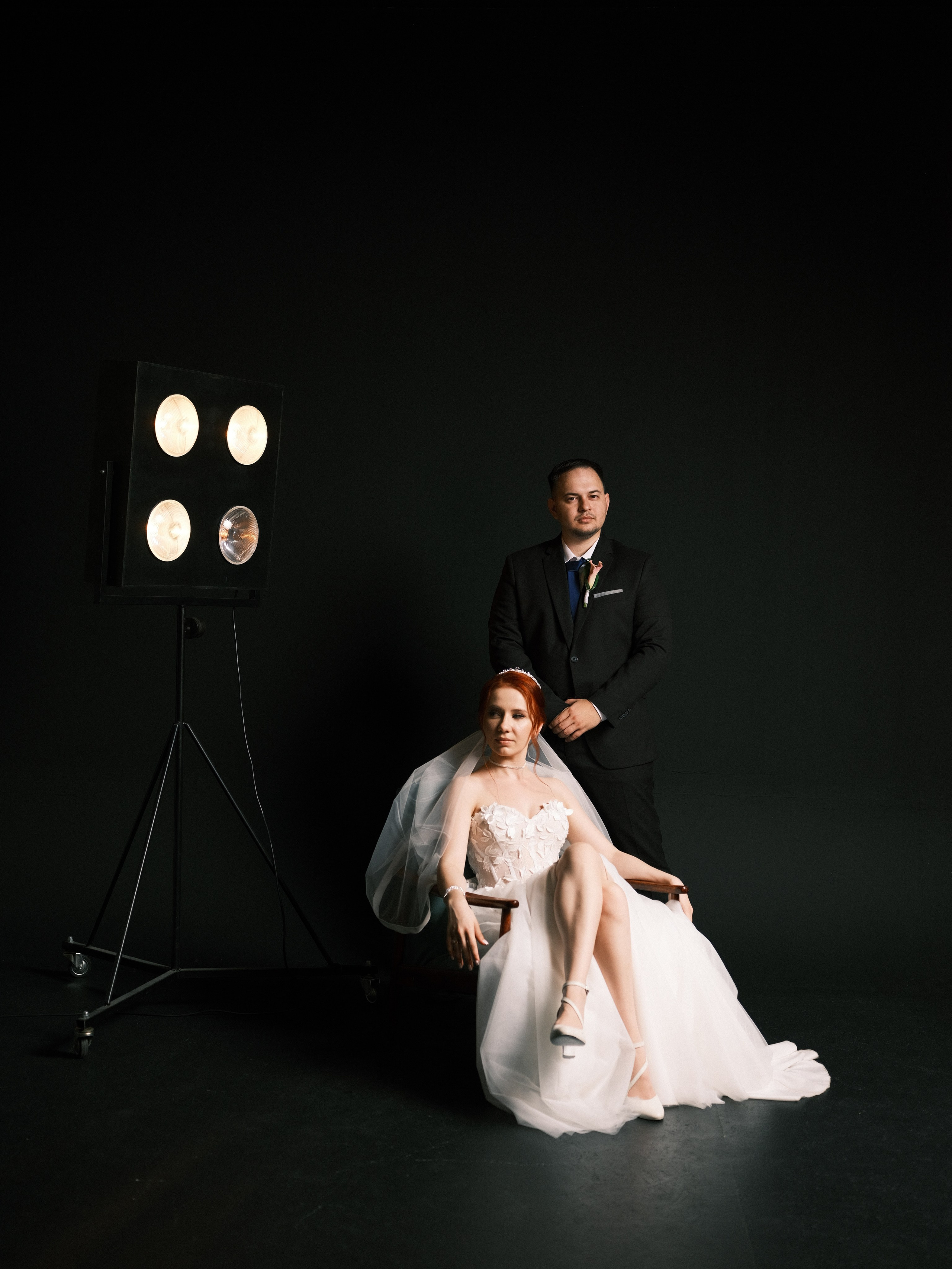 Портрет жениха в синем костюме с бутоньеркой из белых роз на фоне пешеходного моста через Волгу в Волгограде