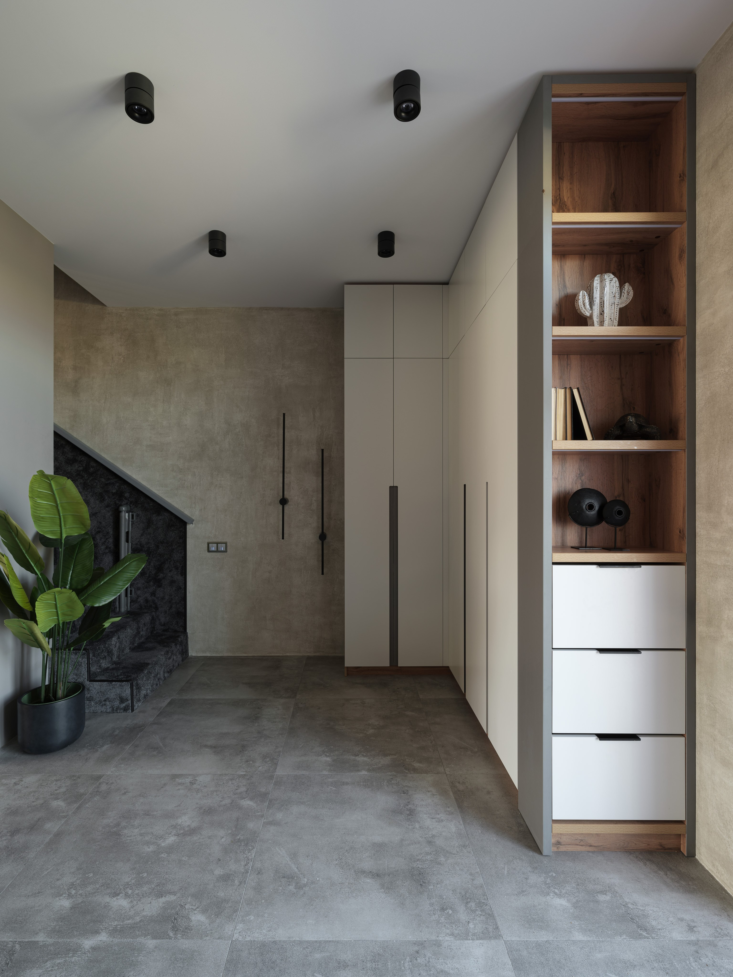 Прихожая в стиле минимализм с мягким освещением, серыми стенами и деревянными элементами декора. Дизайнер Алина Дёрова, стилист Наталья Якушева, фотограф Сергей Денисенко, интерьер с лестницей и нишами.