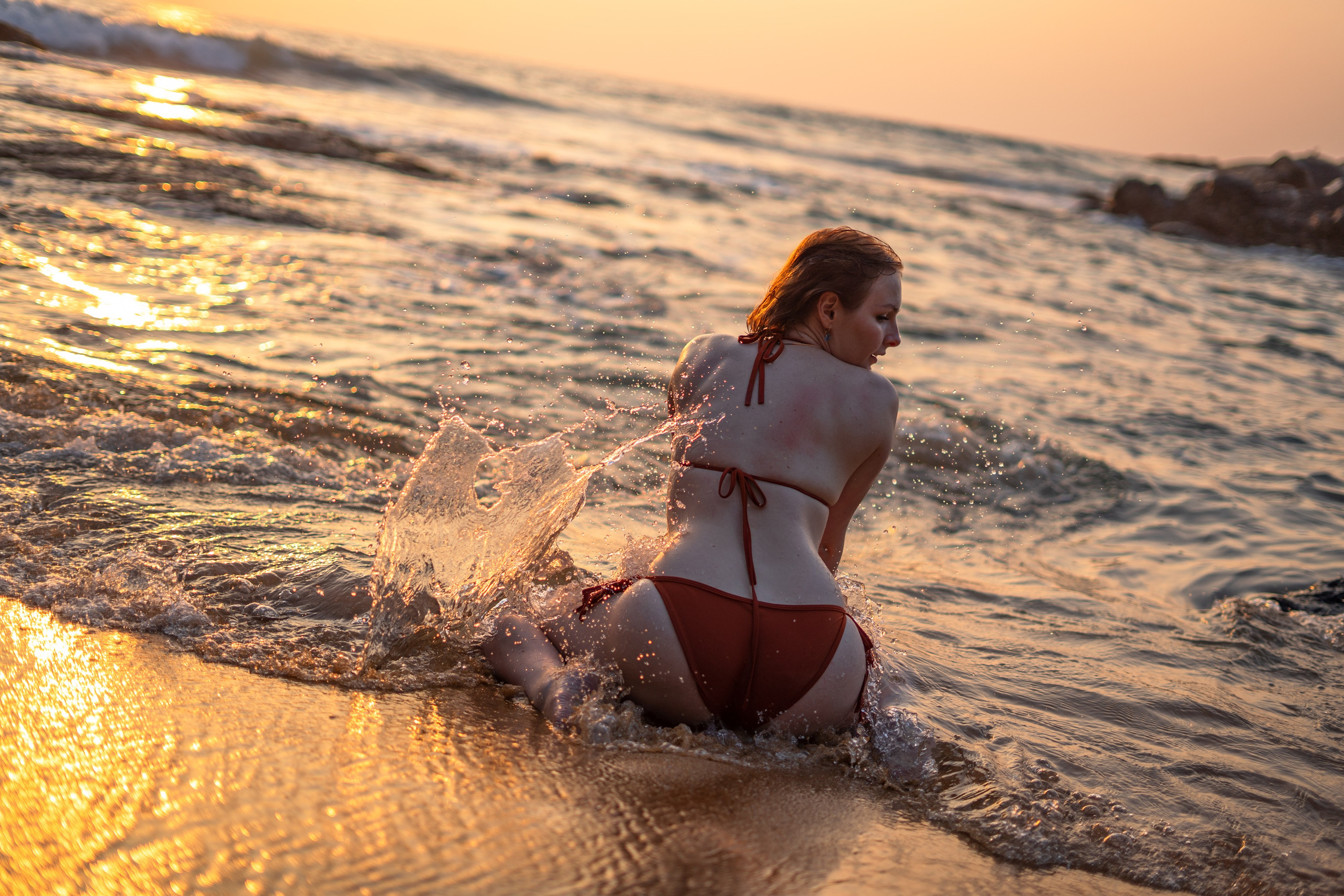 a girl in a red swimsuit with the sunset reflecting in the water