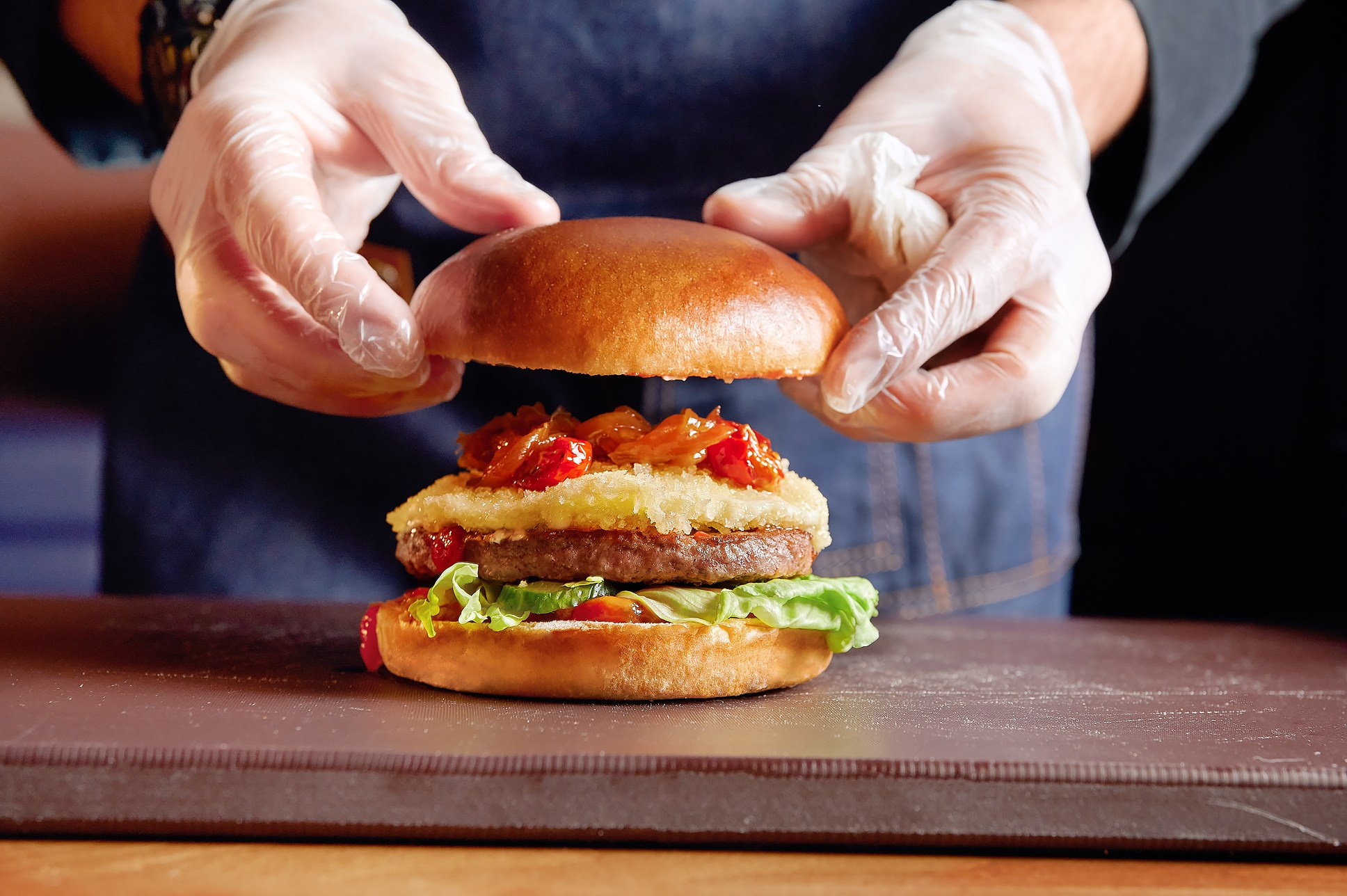 Фотография руки шефа, поливающей соусом гриль в момент приготовления