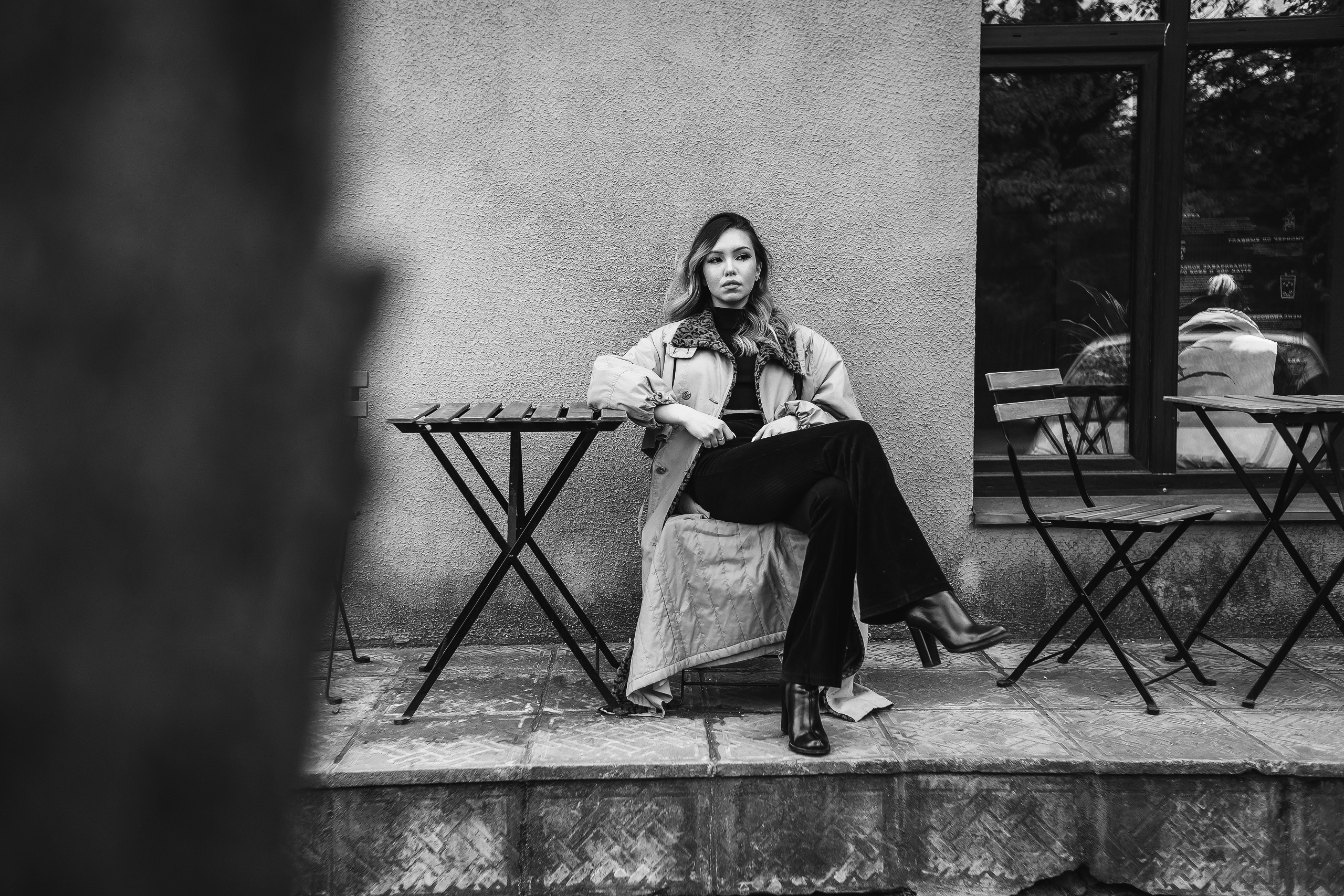 девушка в пальто сидит за столиком