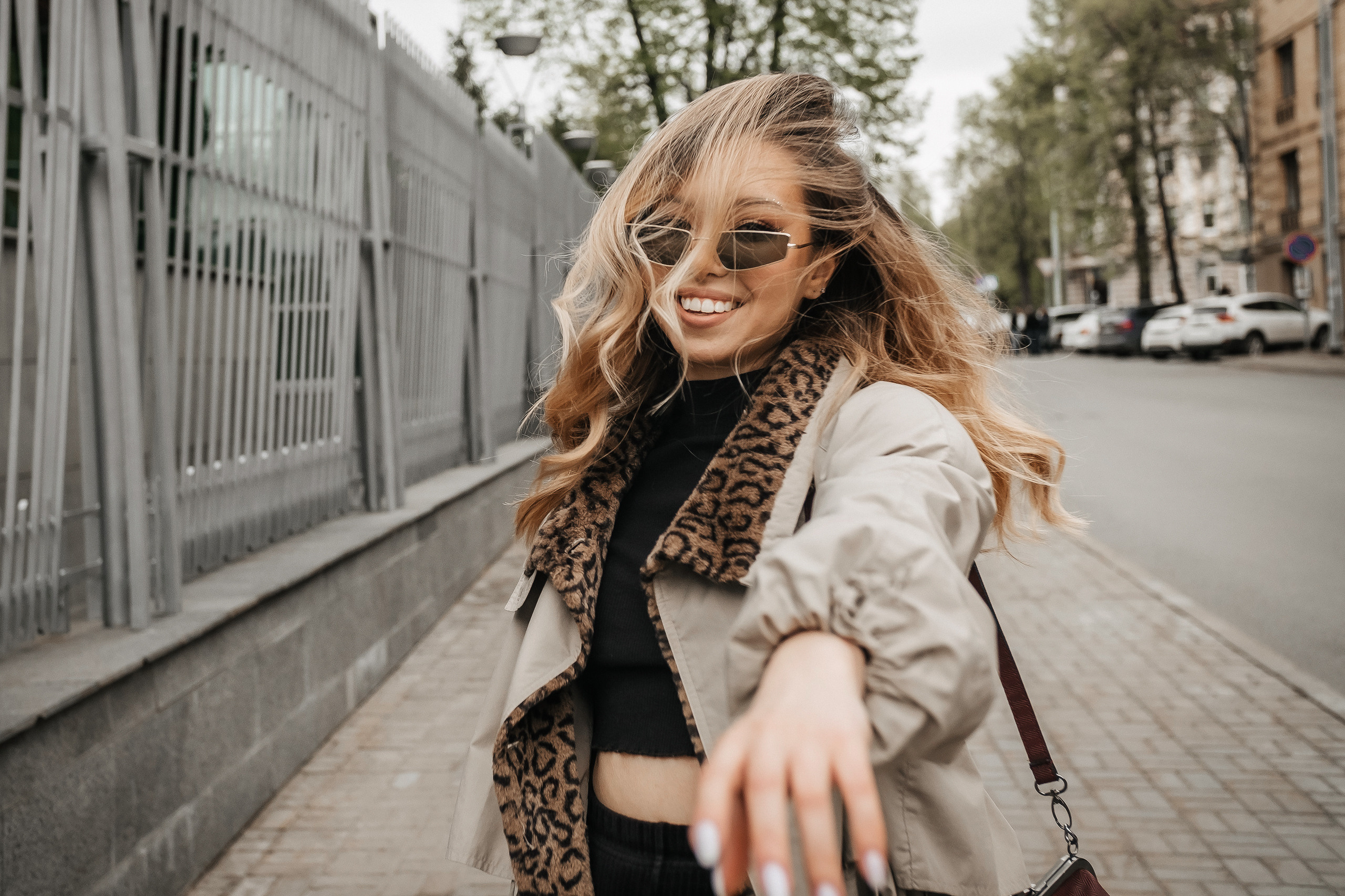 девушка в очках и пальто гуляет по городу