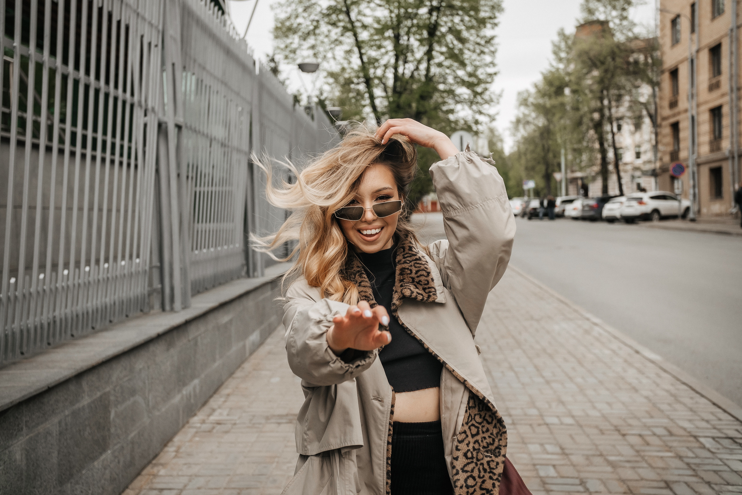 девушка в очках и пальто гуляет по городу