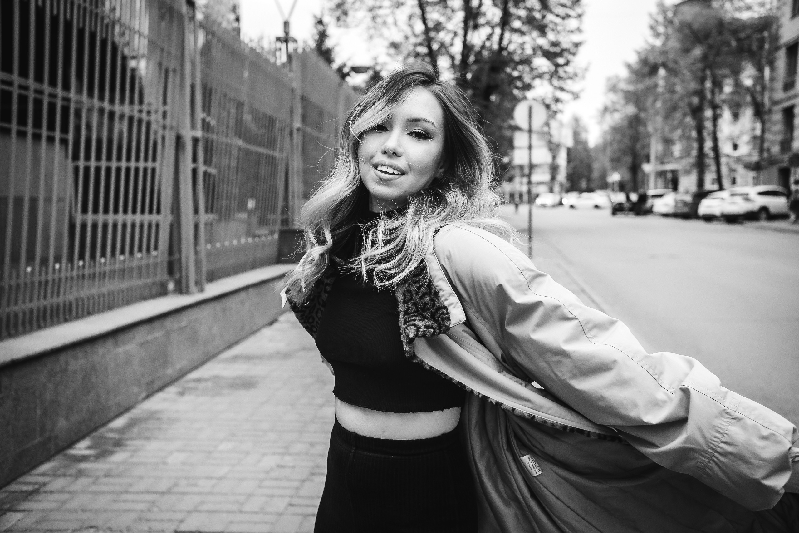 девушка в очках и пальто гуляет по городу