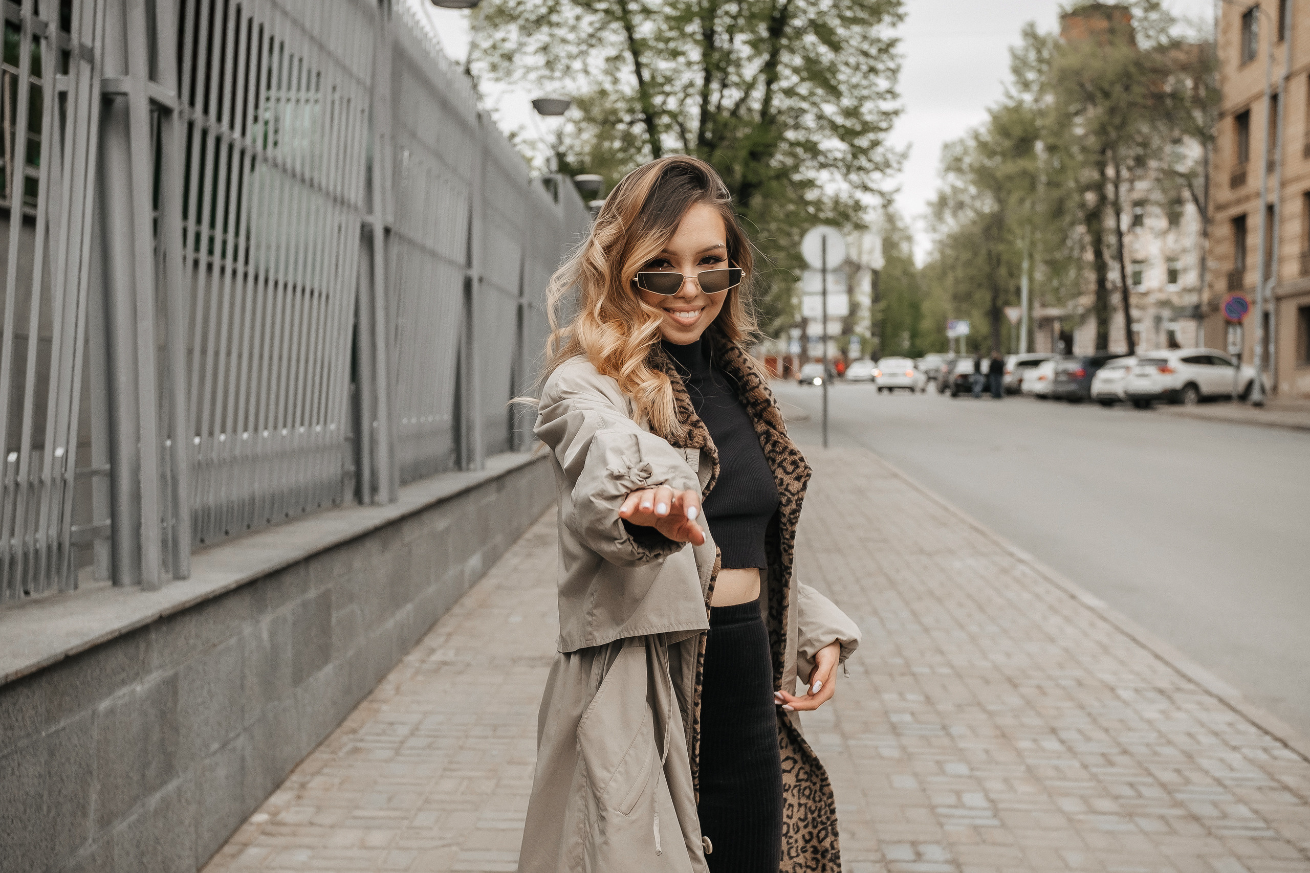 девушка в очках и пальто гуляет по городу