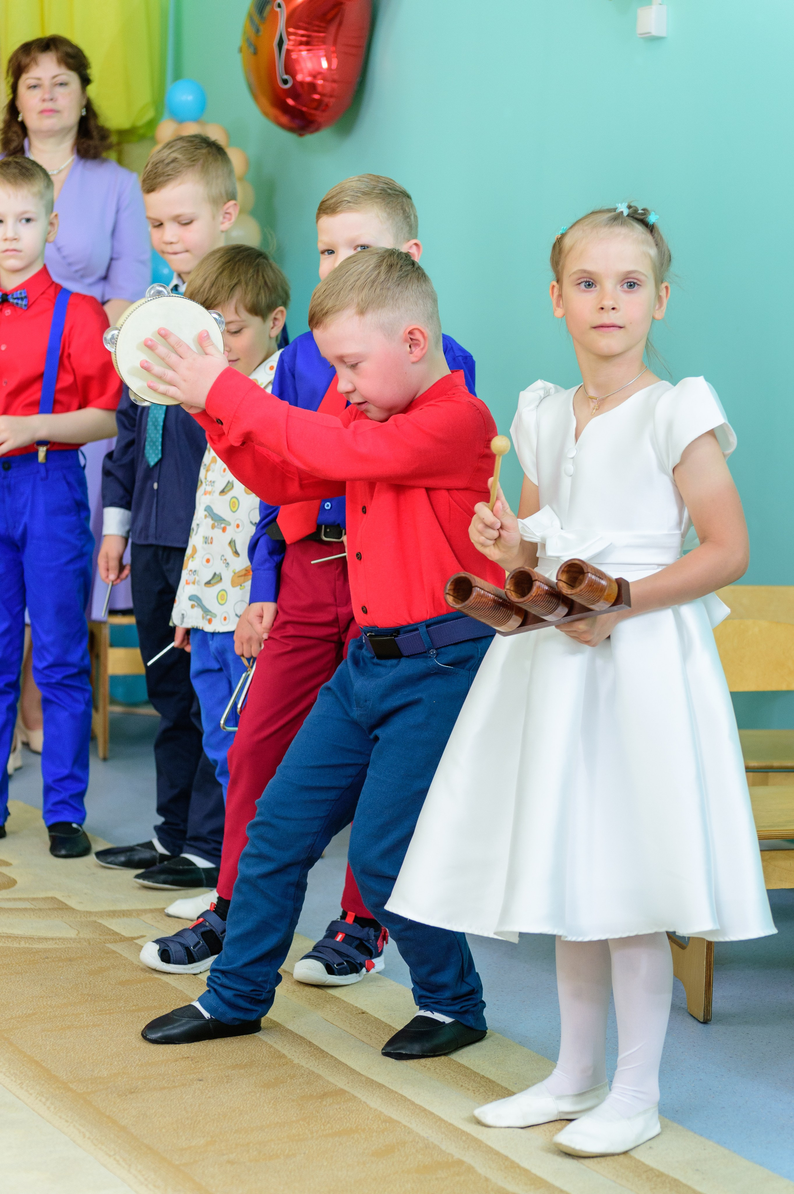 Мальчик демонстрирует умение играть на музыкальном инструменте на утреннике в детском саду.