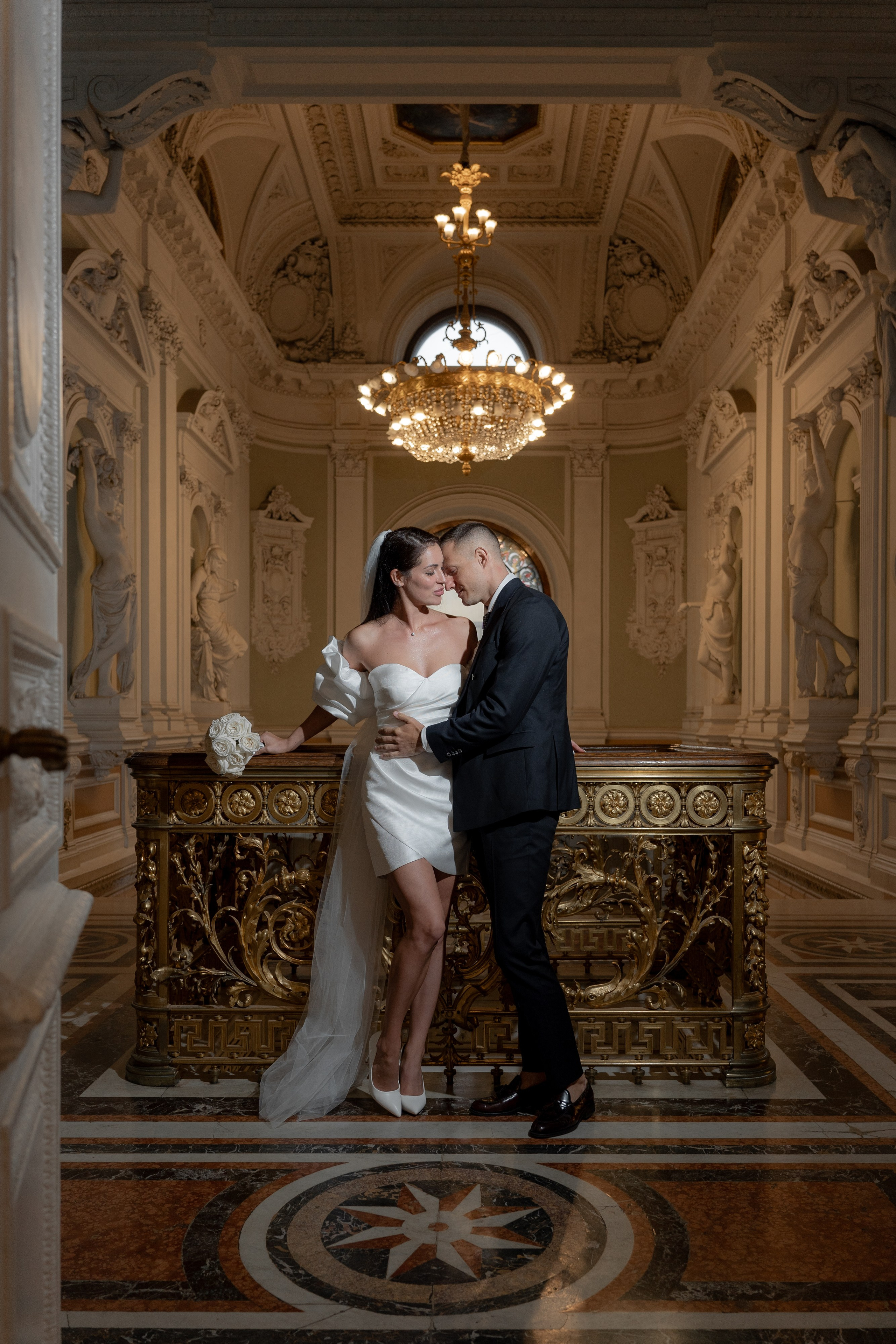 Свадебная фотосессия во Дворце Бракосочетания №1 пара стоит на балконе и позируют фотографу. Фотография в темное время суток в загсе в Санкт-Петербурге.