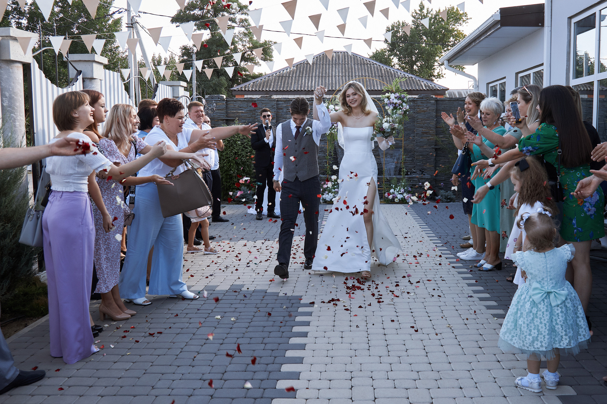 гости бросают лепестки роз на жениха и невесту