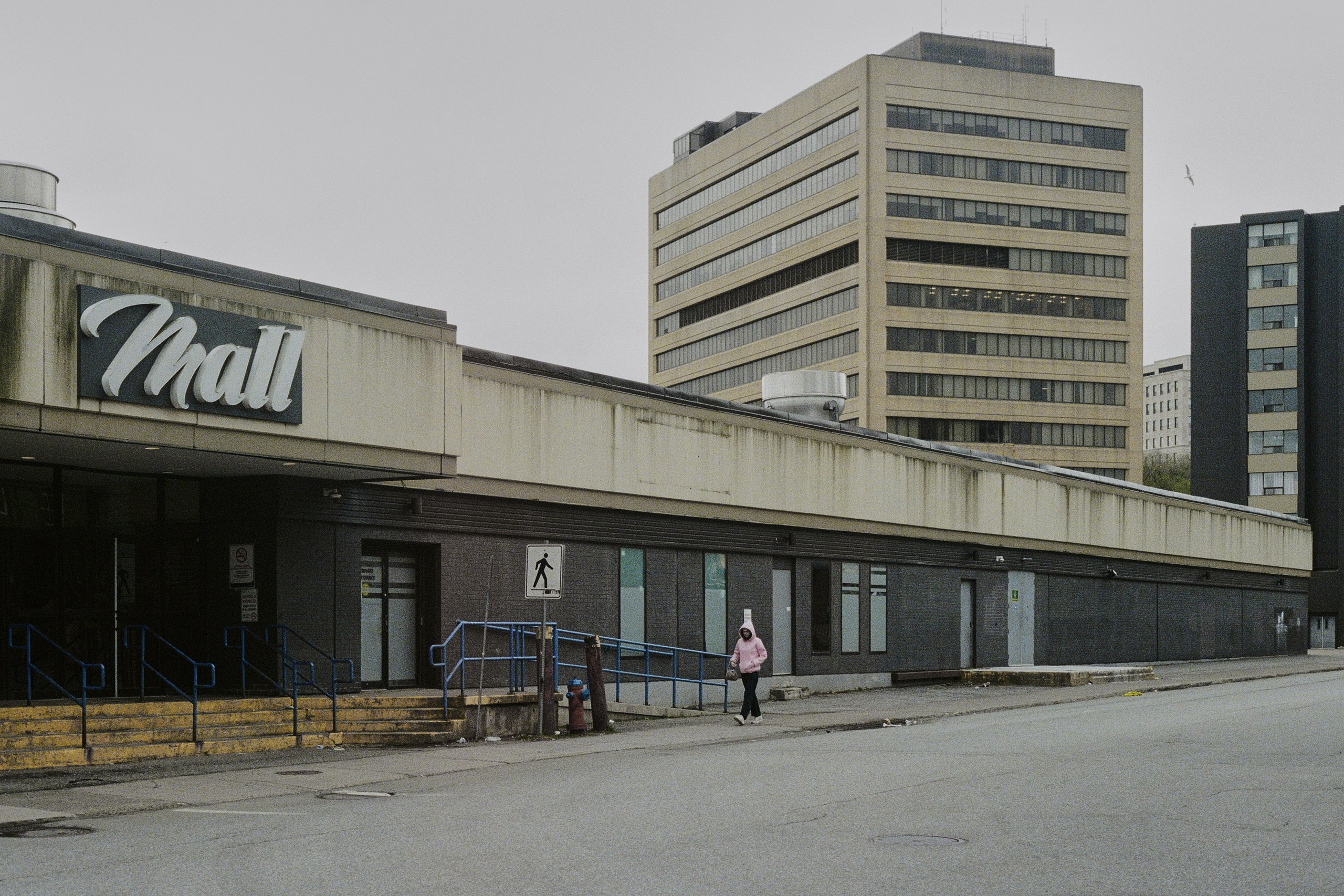 депрессивный городской пейзаж. человек идет на фоне серых бетонных зданий