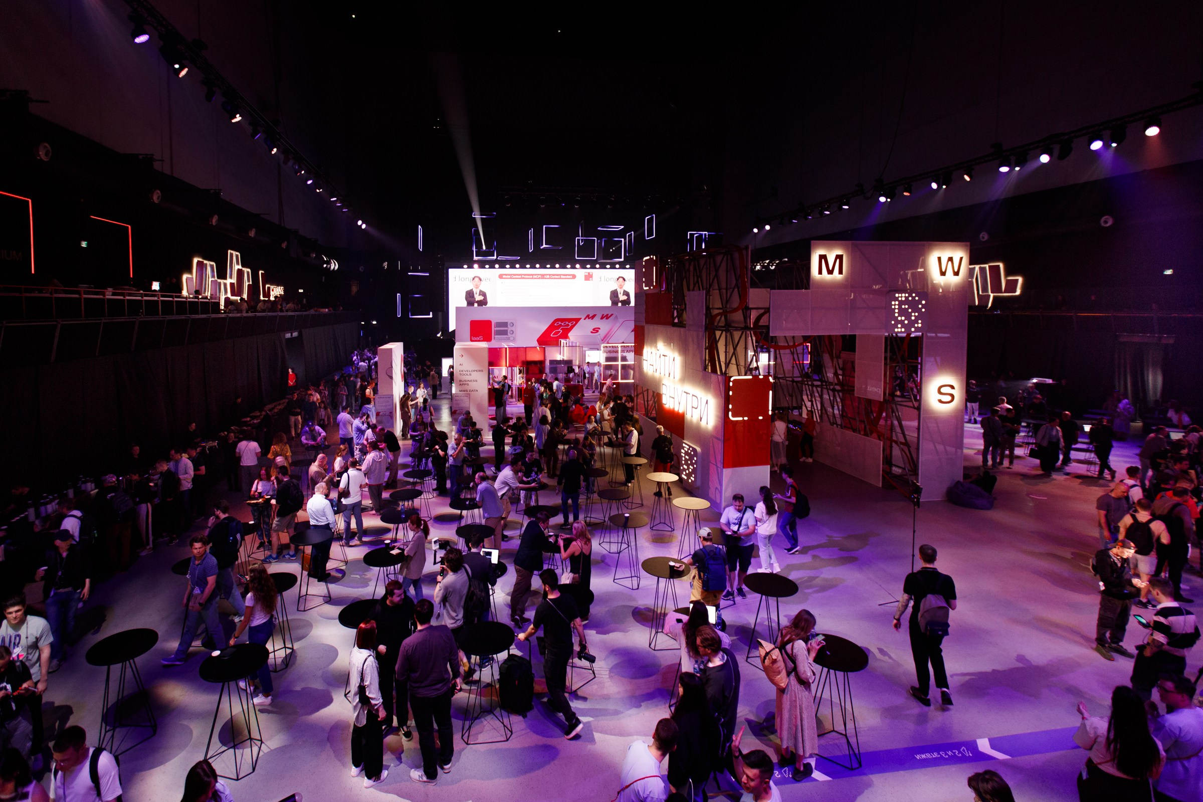 Высокая точка съемки выставочного пространства с ярким фиолетовым и красным светом.