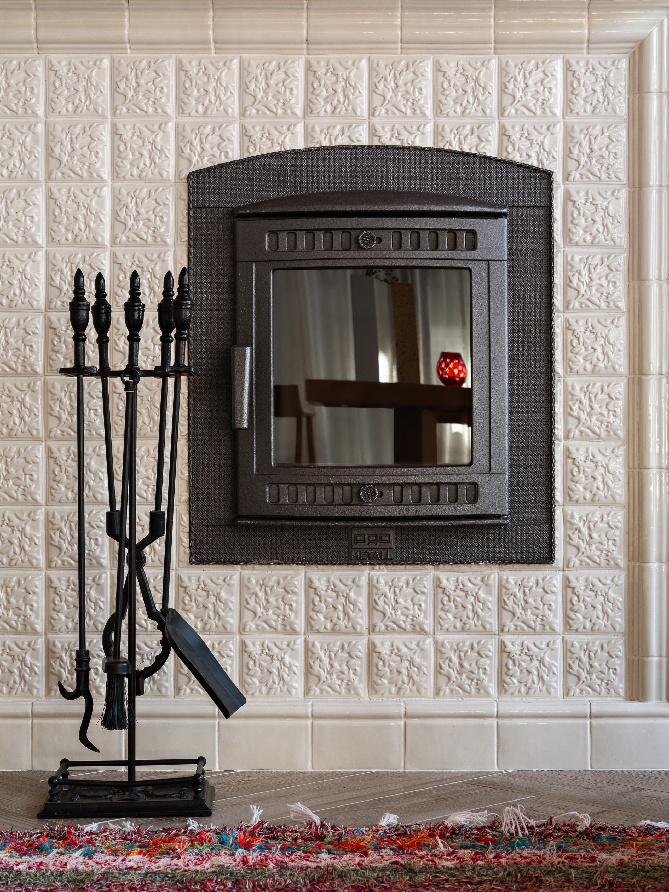 Современный камин в гостиной с отделкой плиткой с растительным орнаментом и коваными аксессуарами; акцент в интерьере от Наталии Шелепниковой, стилист София Калбазова, фотограф Сергей Денисенко.