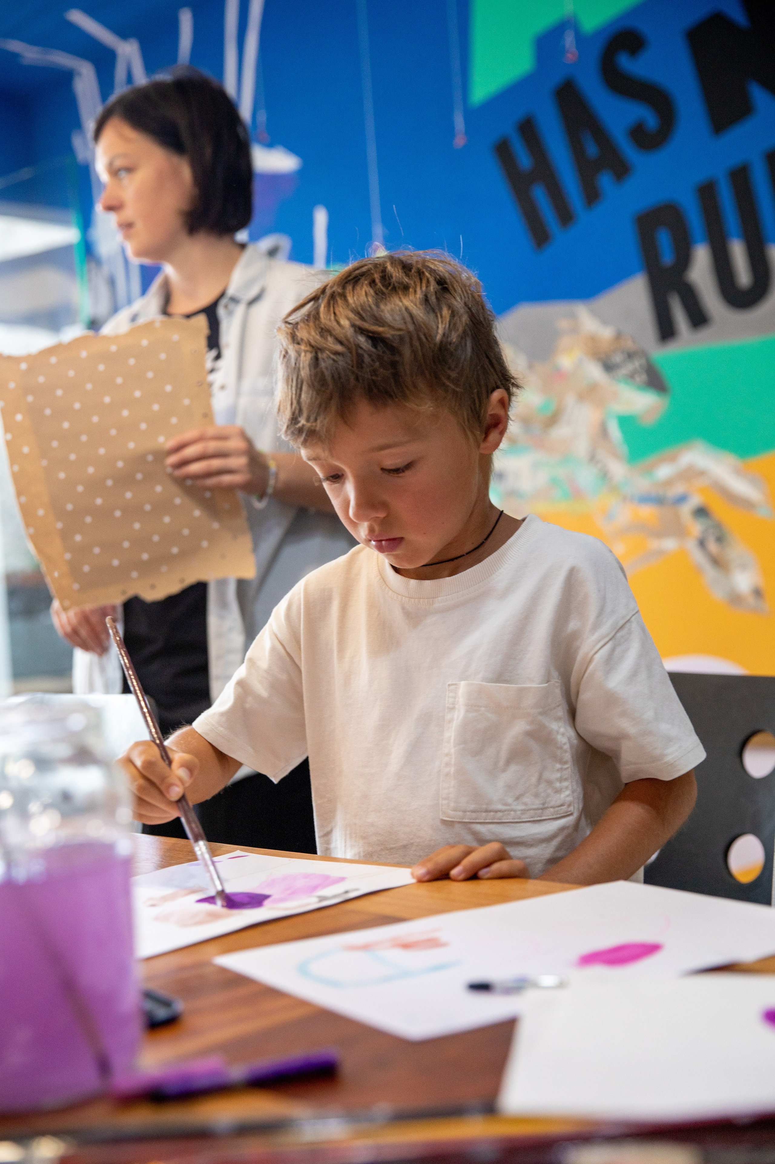 The boy paints with colours