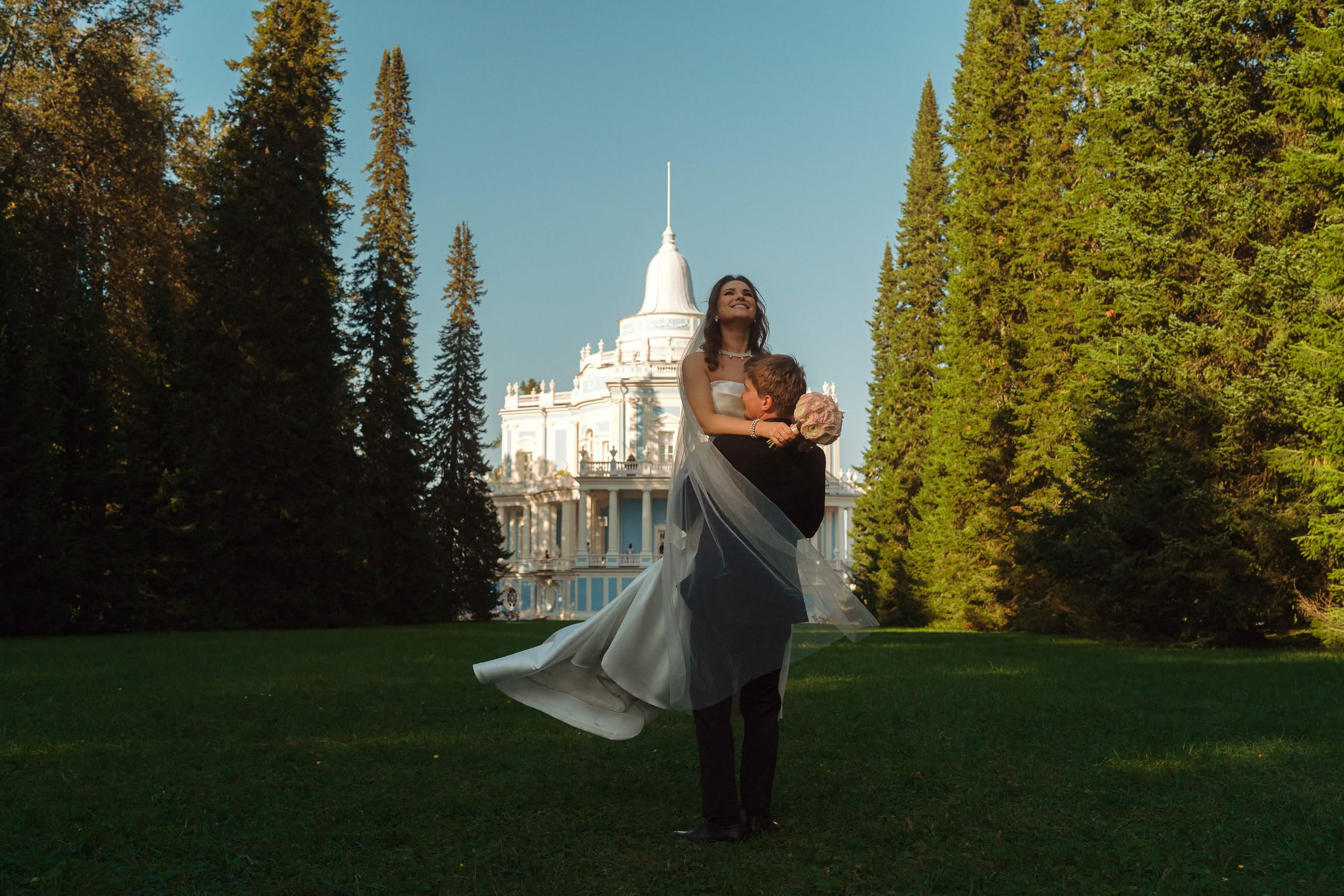 Жених кружит невесту на фоне дворца в Ораниенбауме, свадебная прогулка в парке