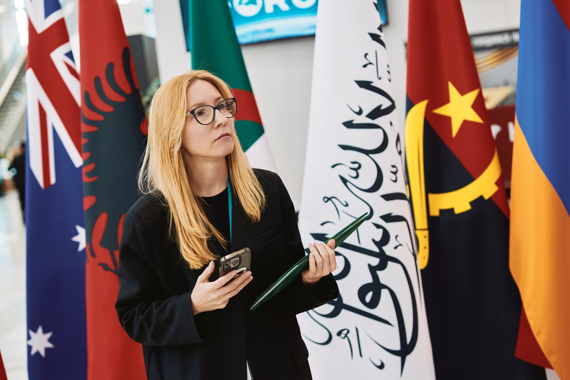 Международные делегаты KazanForum общаются на фоне национальных флагов.