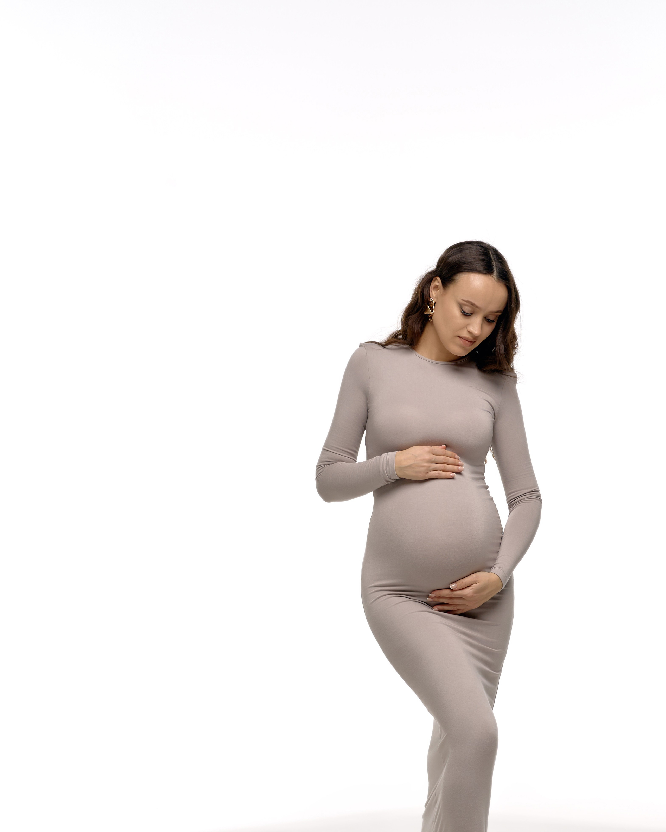 Платье для беременных: длинное облегающее серое платье, фотосессия будущей мамы, стильный образ на белом фоне