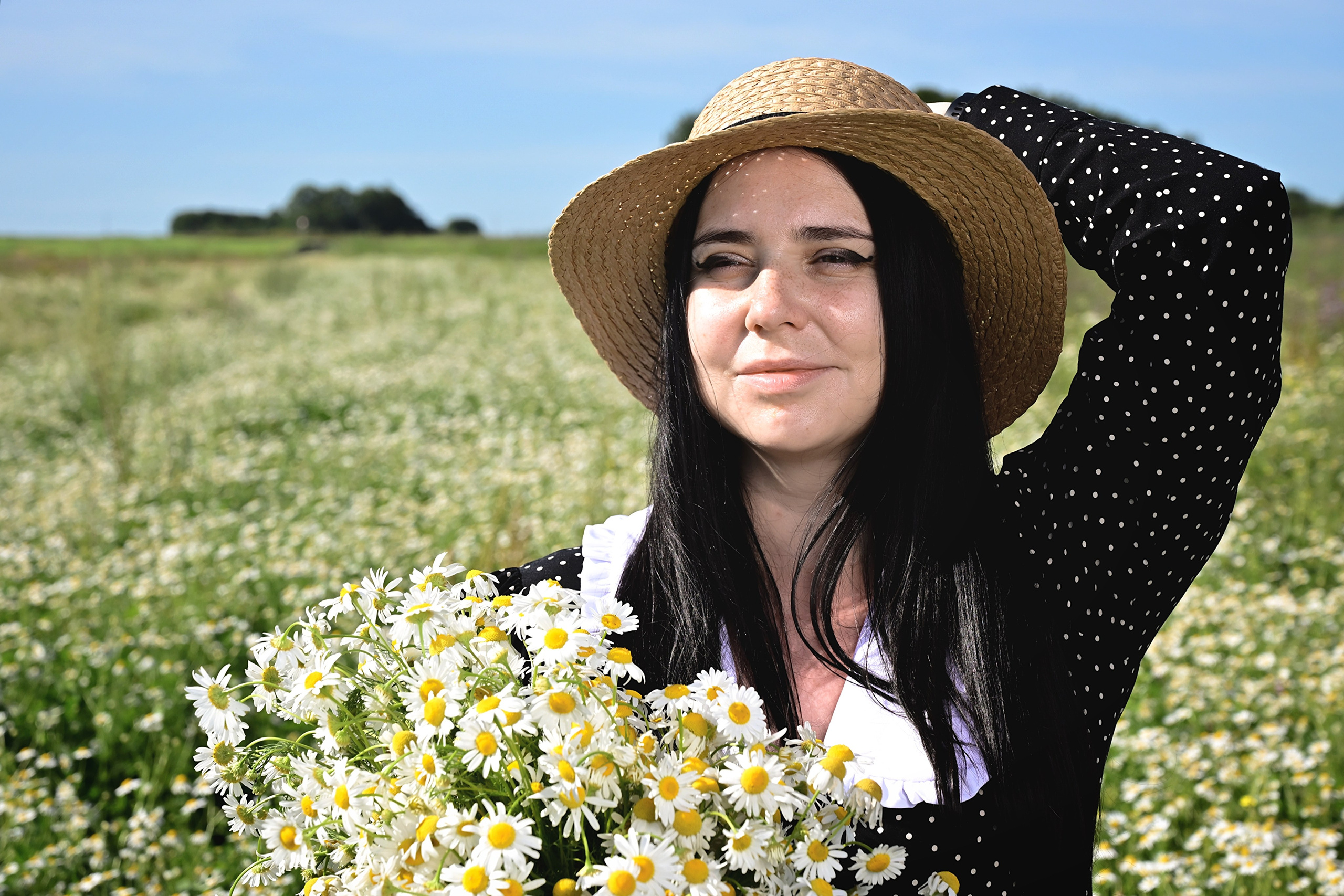 Девушка в шляпе в поле в шляпе с букетом ромашек