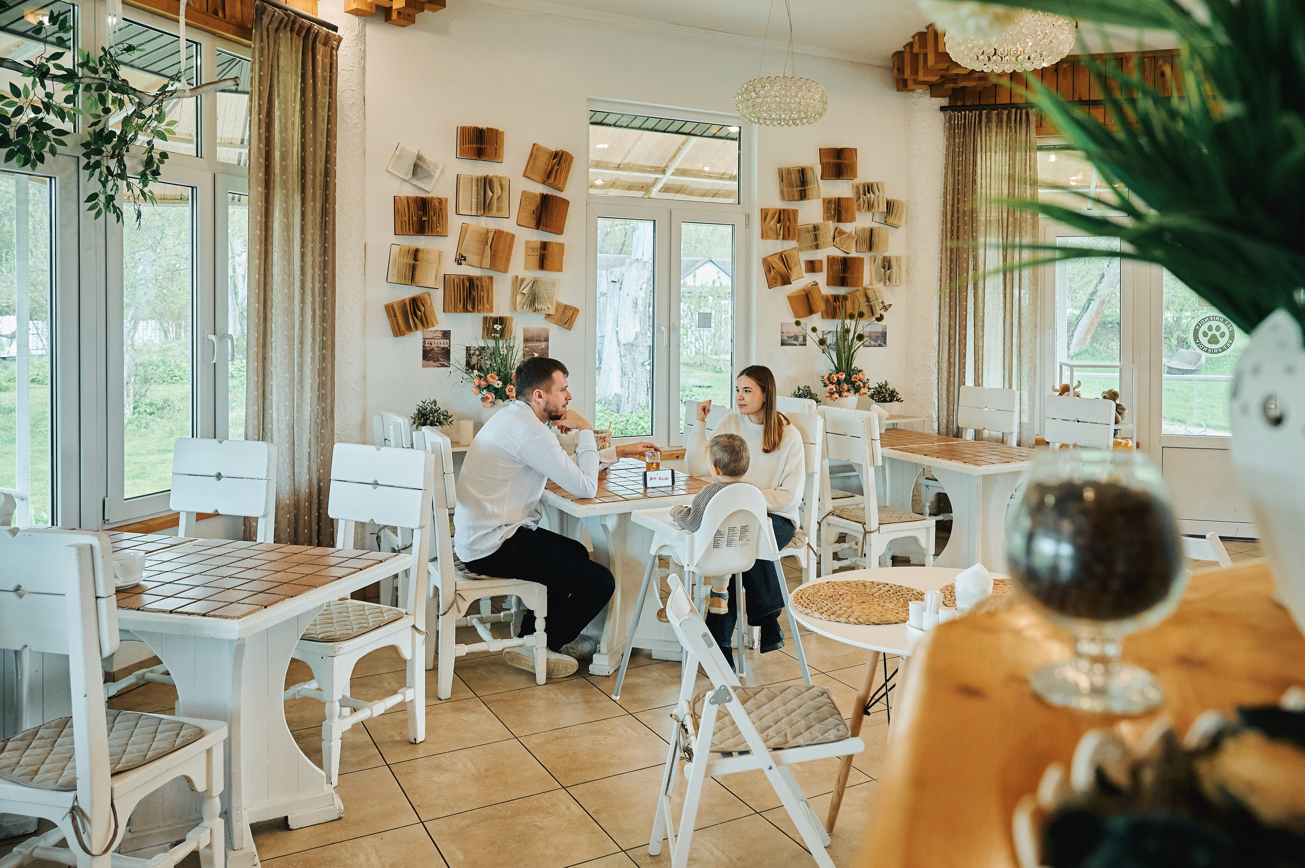 Семья из трёх человек сидит за столом в кафе, мальчик в детском стульчике