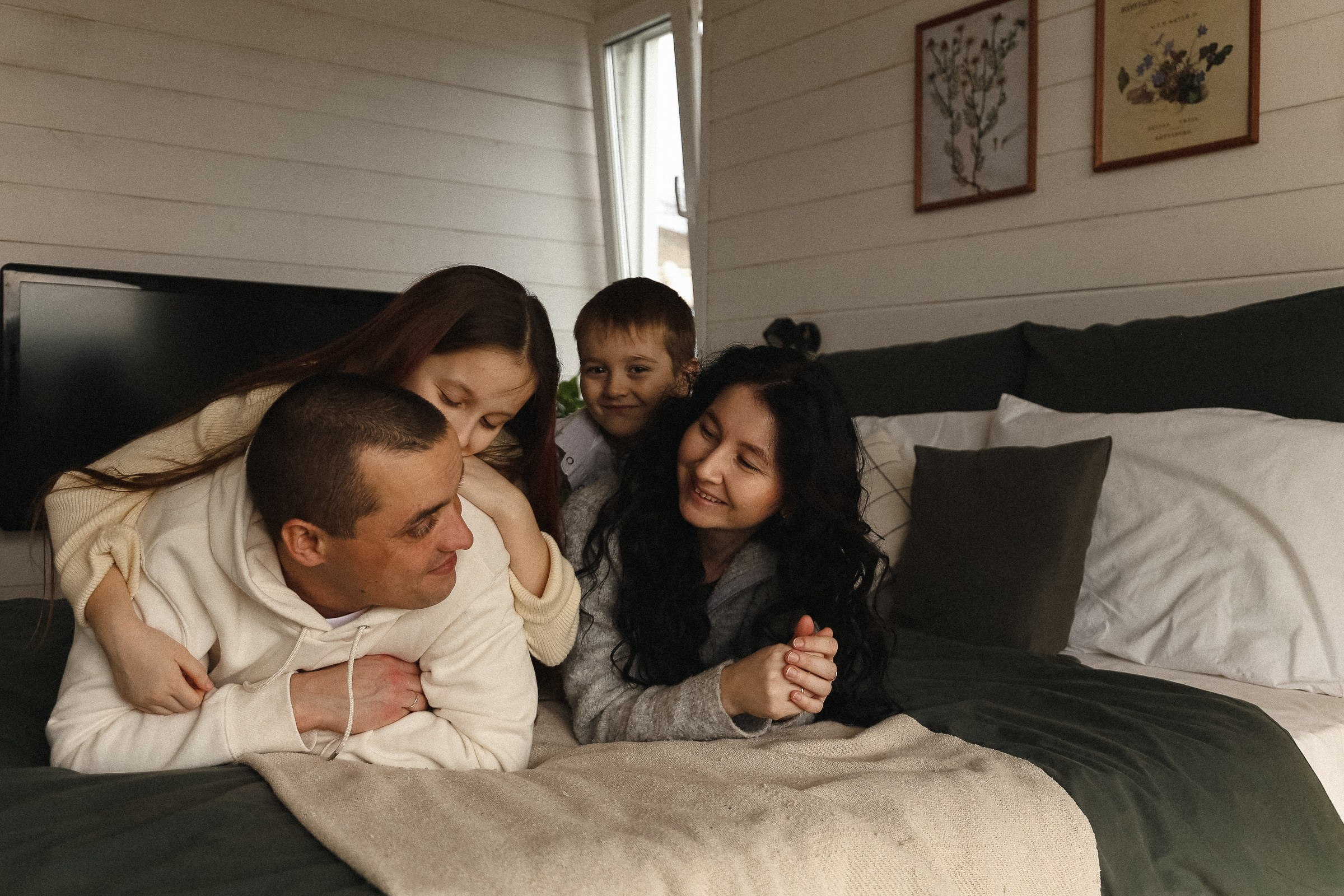 Семья лежит на кровати