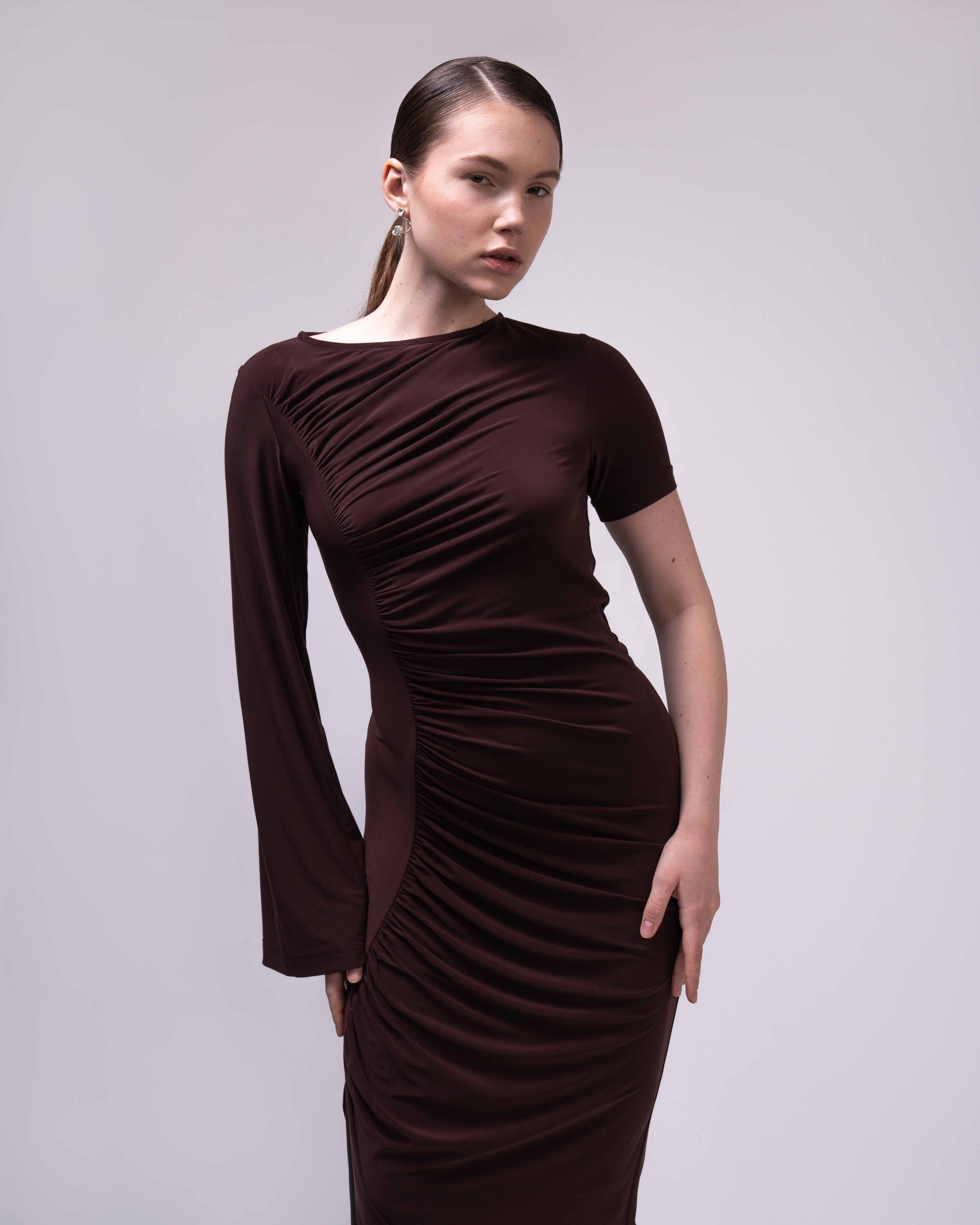 Фото товара для каталога  Ozon или Wildberries.  На изображении представлена женщина, одетая в коричневое платье с длинными рукавами. Платье имеет облегающий силуэт и драпировку на груди. Фон нейтральный, светлый.