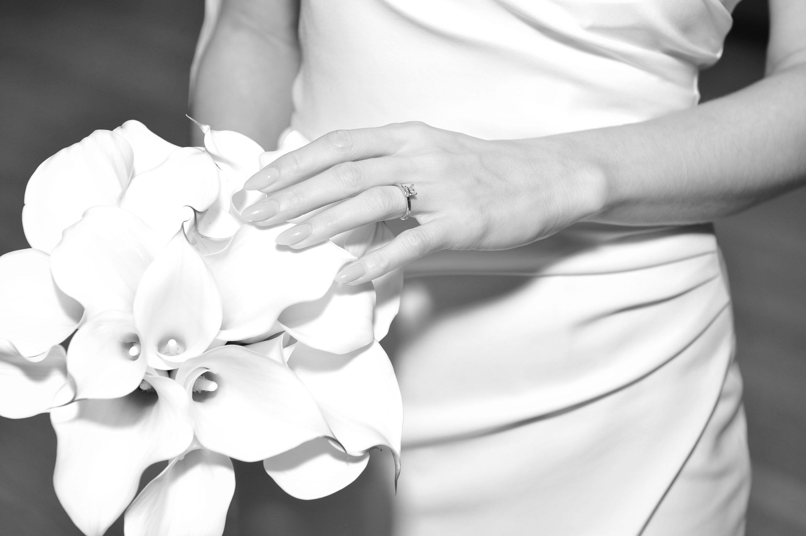 Рука невесты в белом платье на белом букете черно-белая свадебная фотография