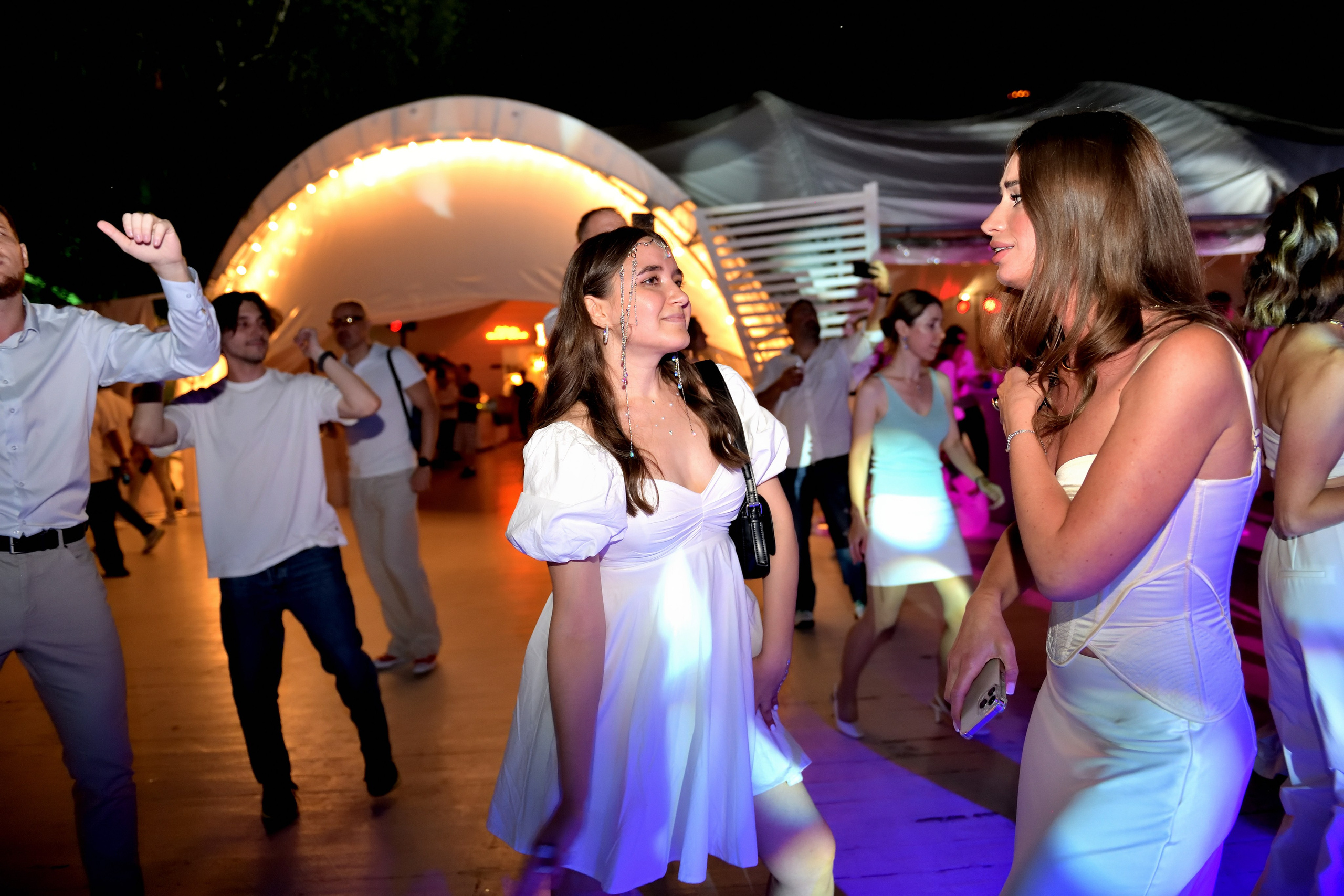 "Девушки танцуют под музыку на летнем корпоративе".