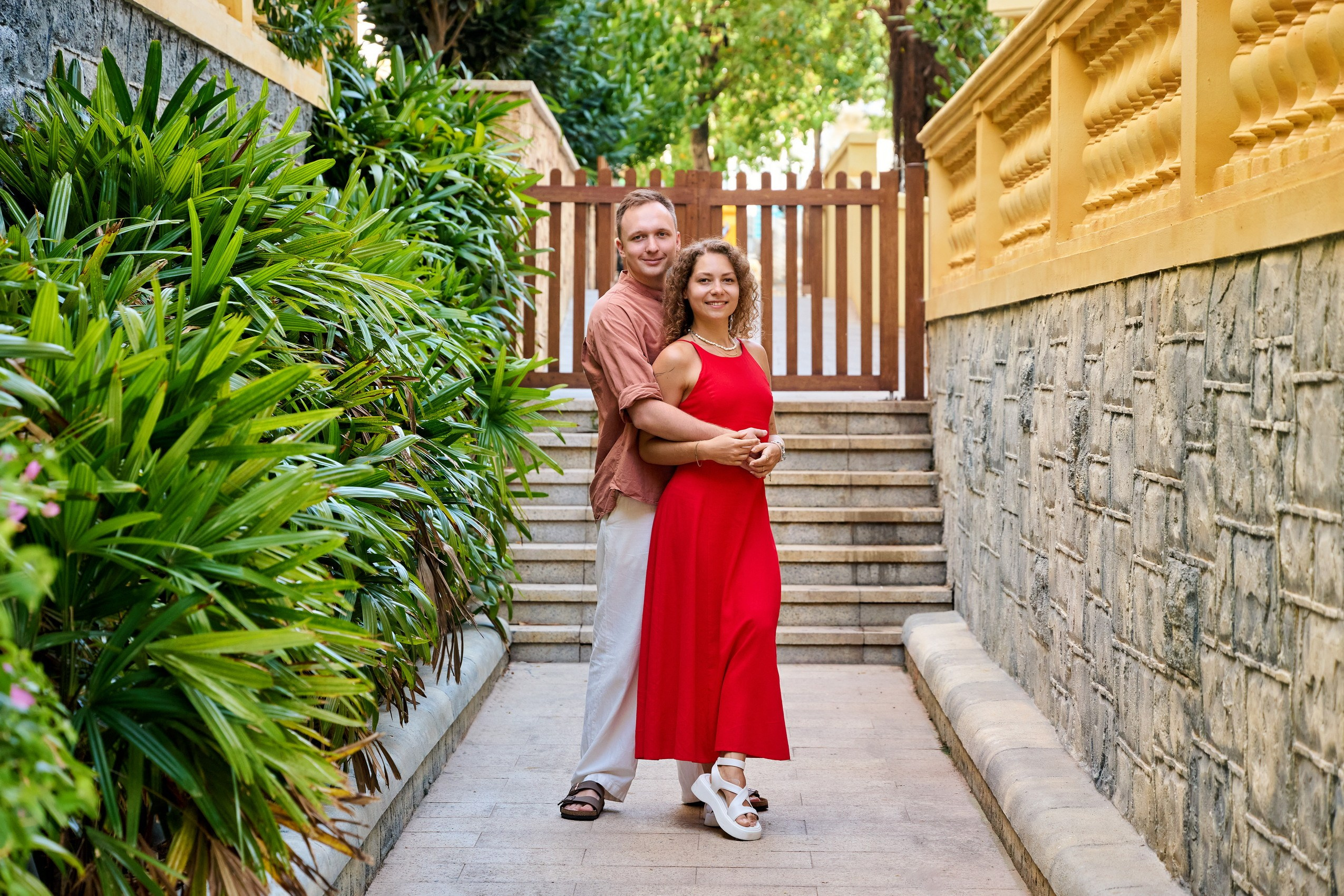 Embracing couple in front of wooden gate during Sunset Town photoshoot, Phu Quoc.