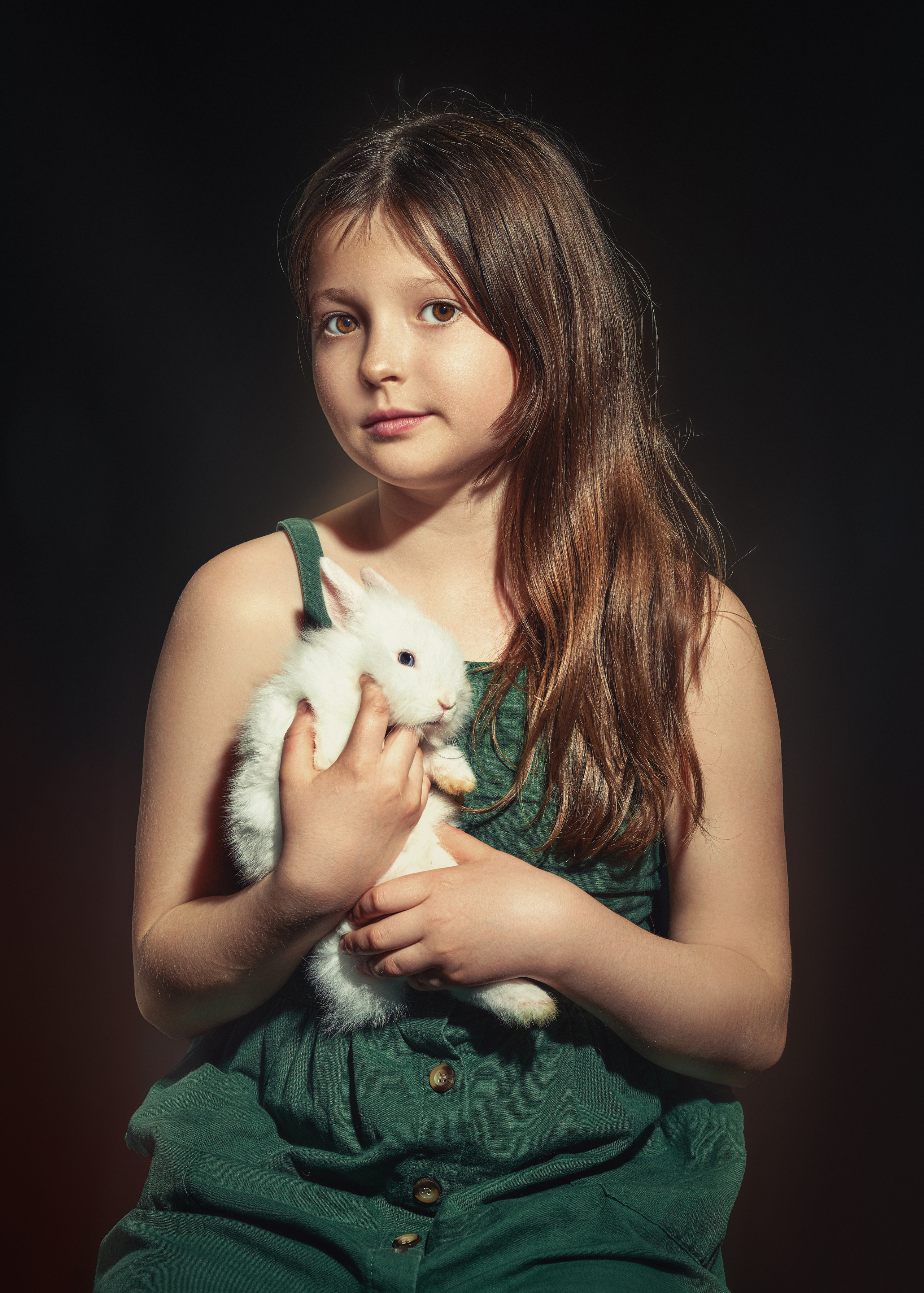 Ребенок девочка в комбинезоне с кроликом на руках