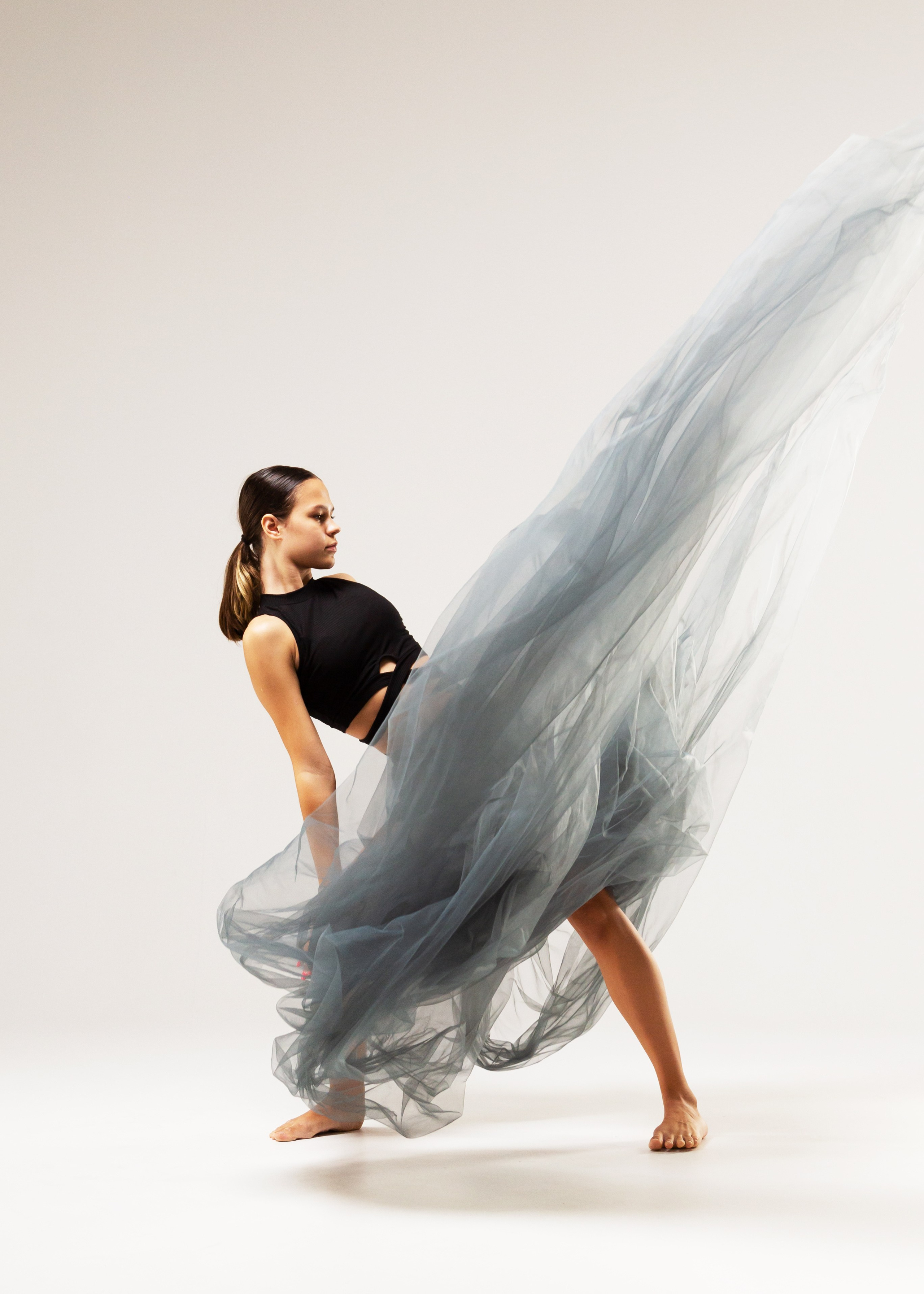 Элегантная балетная фотография танцовщицы в движении, грациозный танец с вуалью на фоне белого студия
