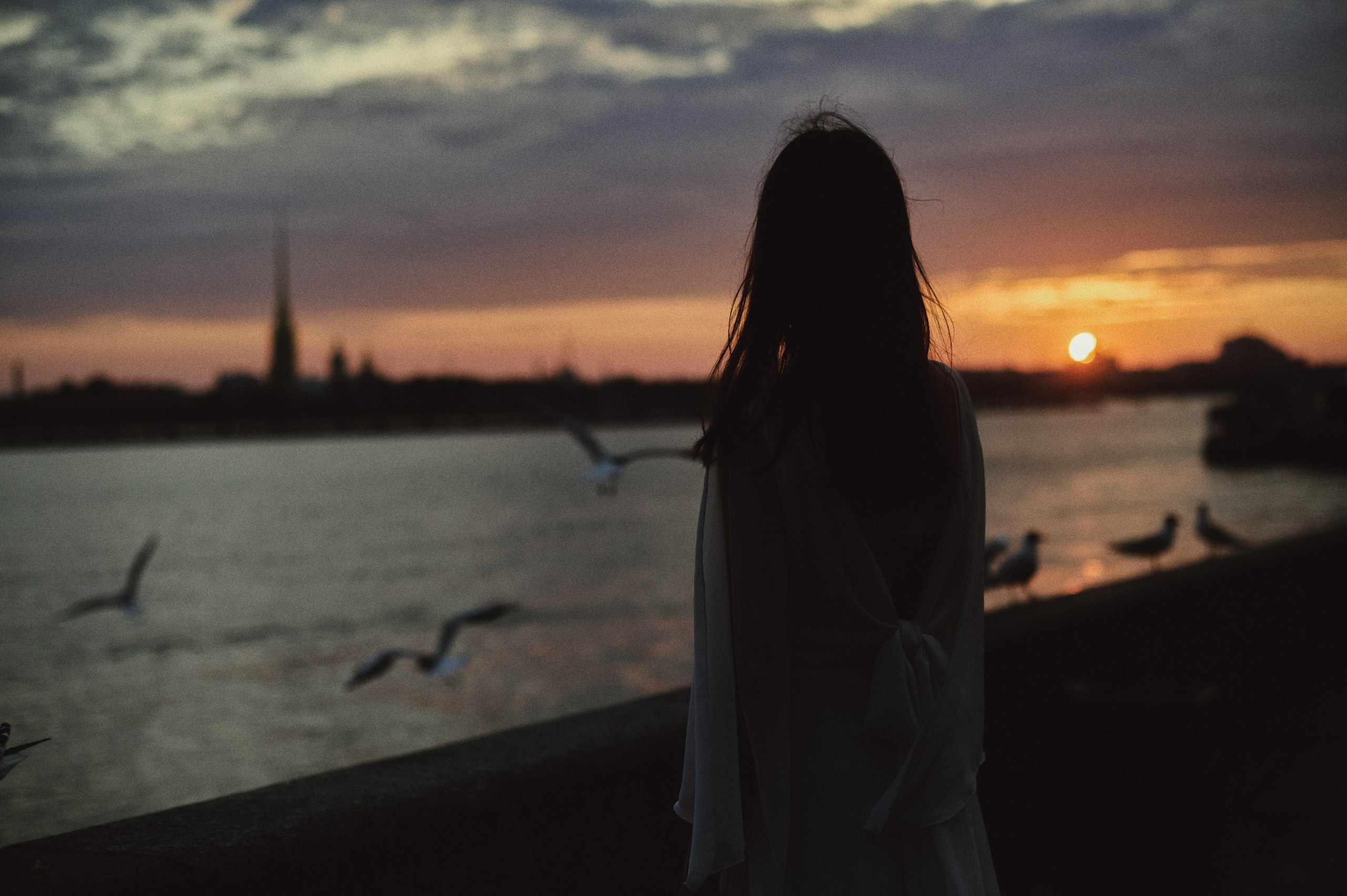 Девушка смотрит на закат на дворцовой набережной