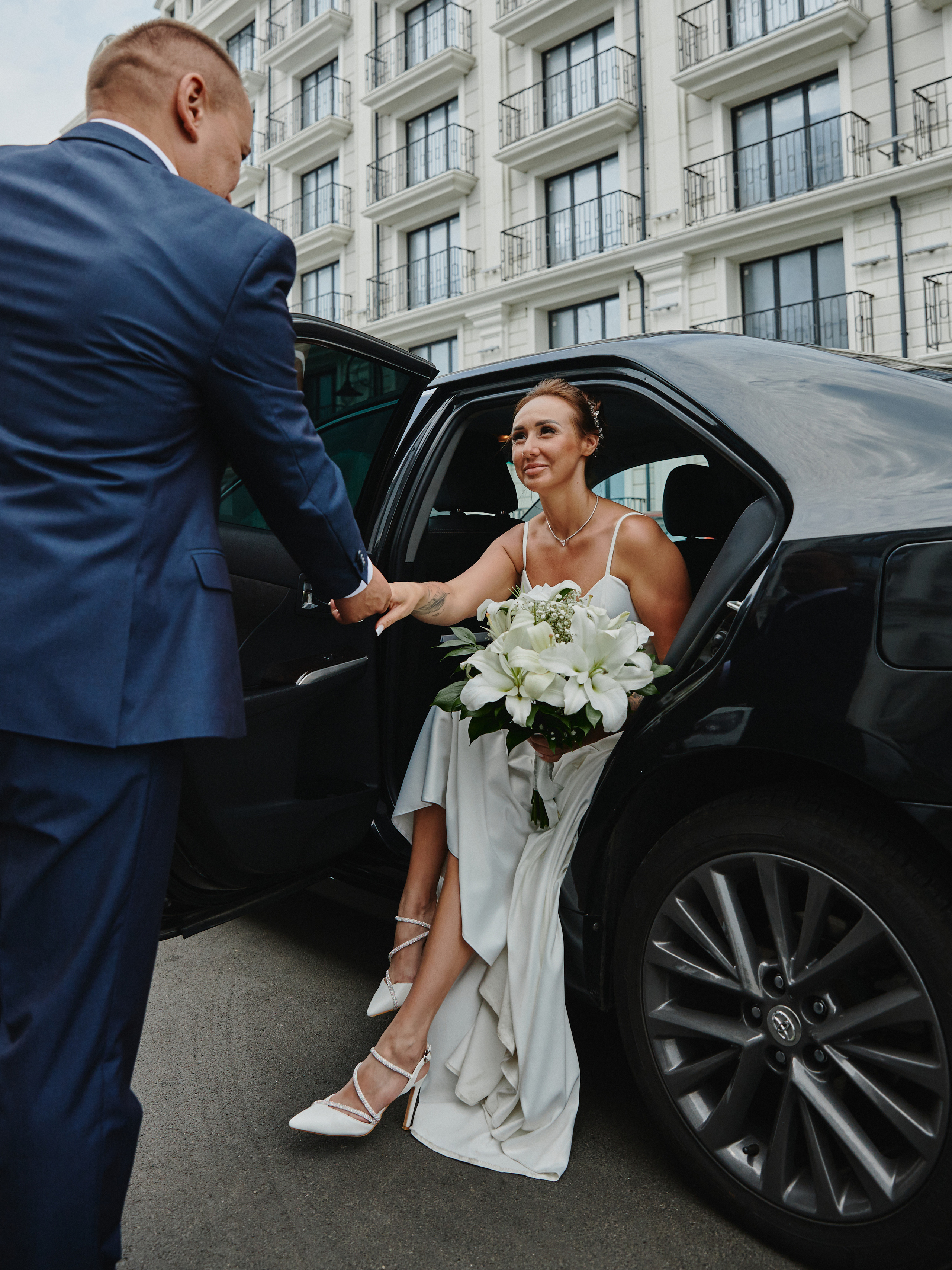Жених помогает невесте выйти из автомобиля