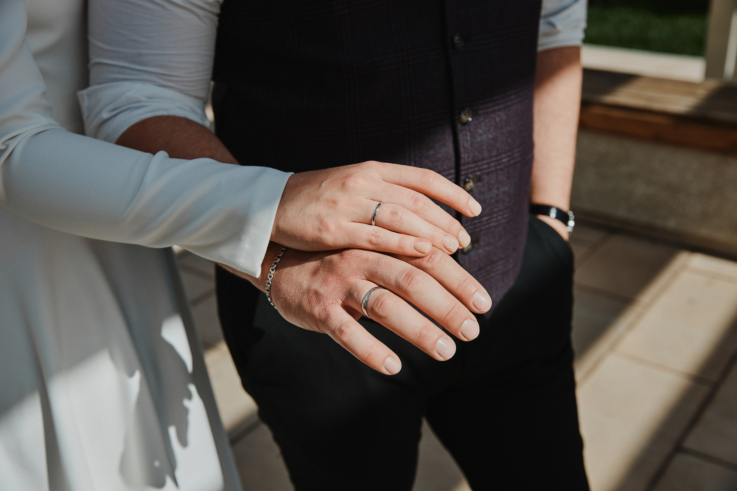 Руки молодоженов с обручальными кольцами на солнце