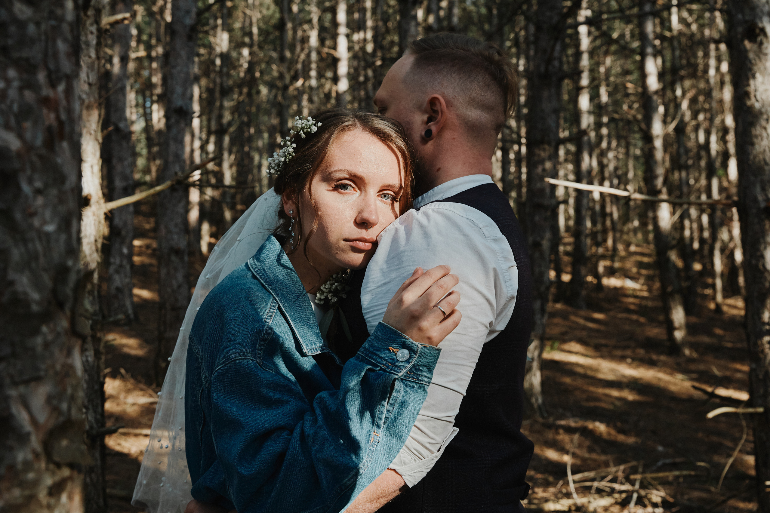 Невеста прижимается к груди жениха и смотрит в камеру