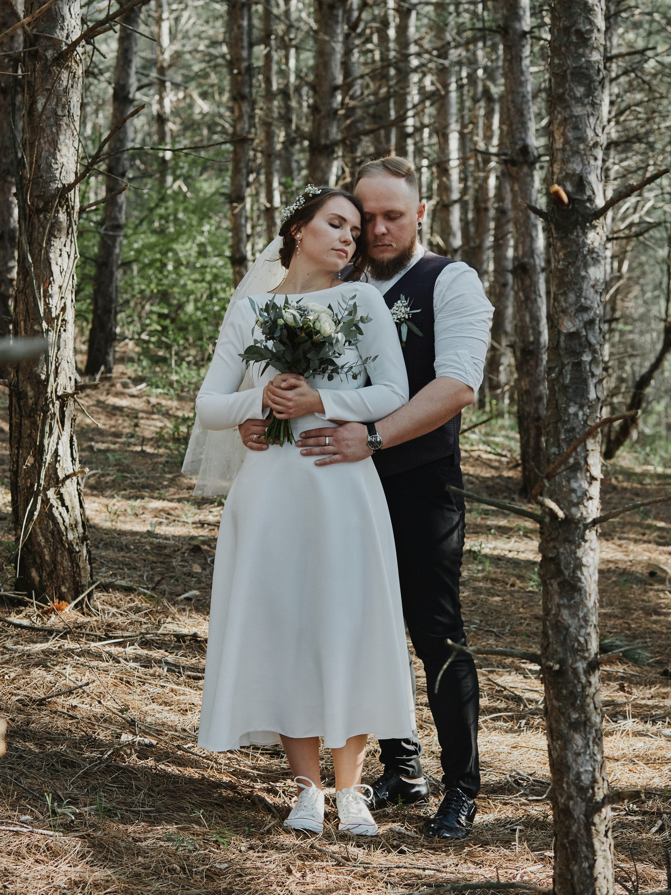 Жених обнимает невесту в лесу