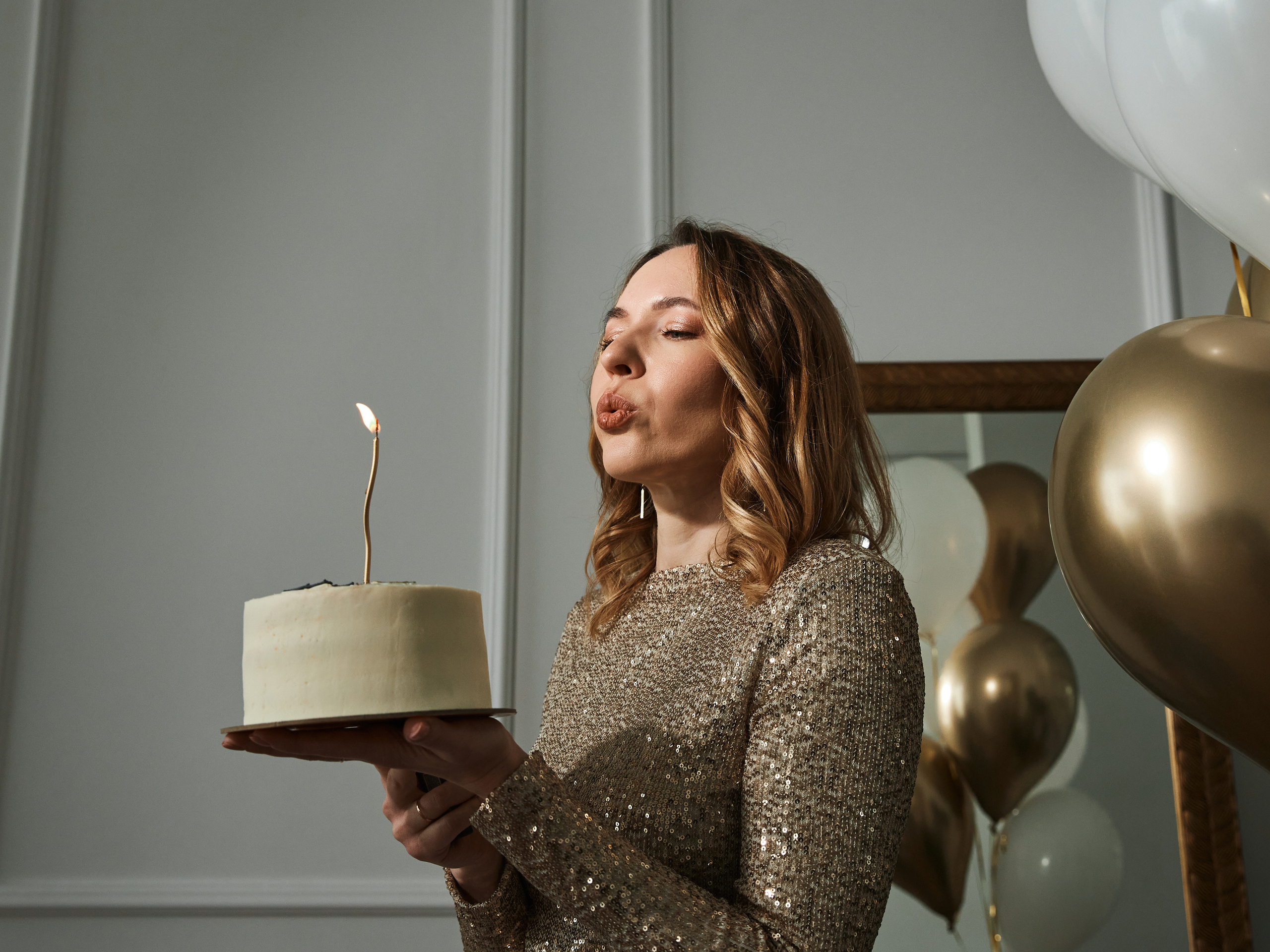 Девушка задувает свечи на торте в фотостудии в Анапе