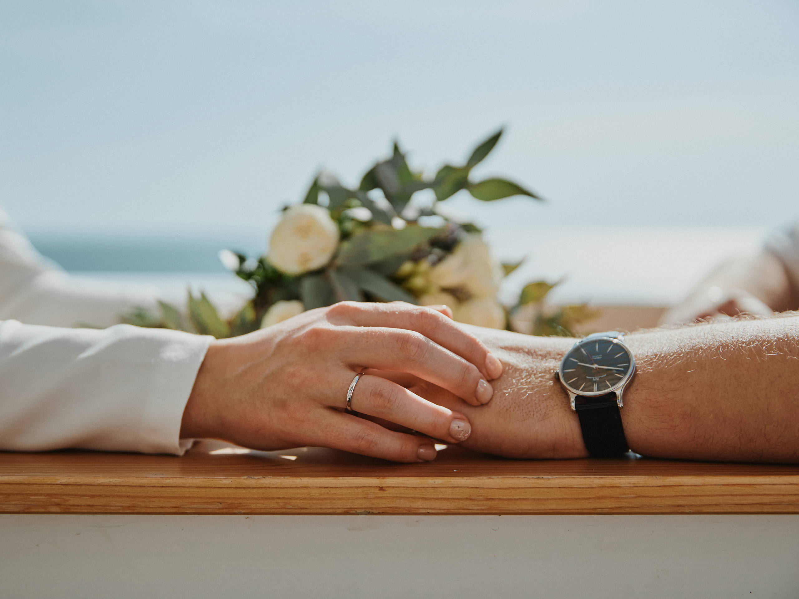 Руки молодоженов и свадебный букет