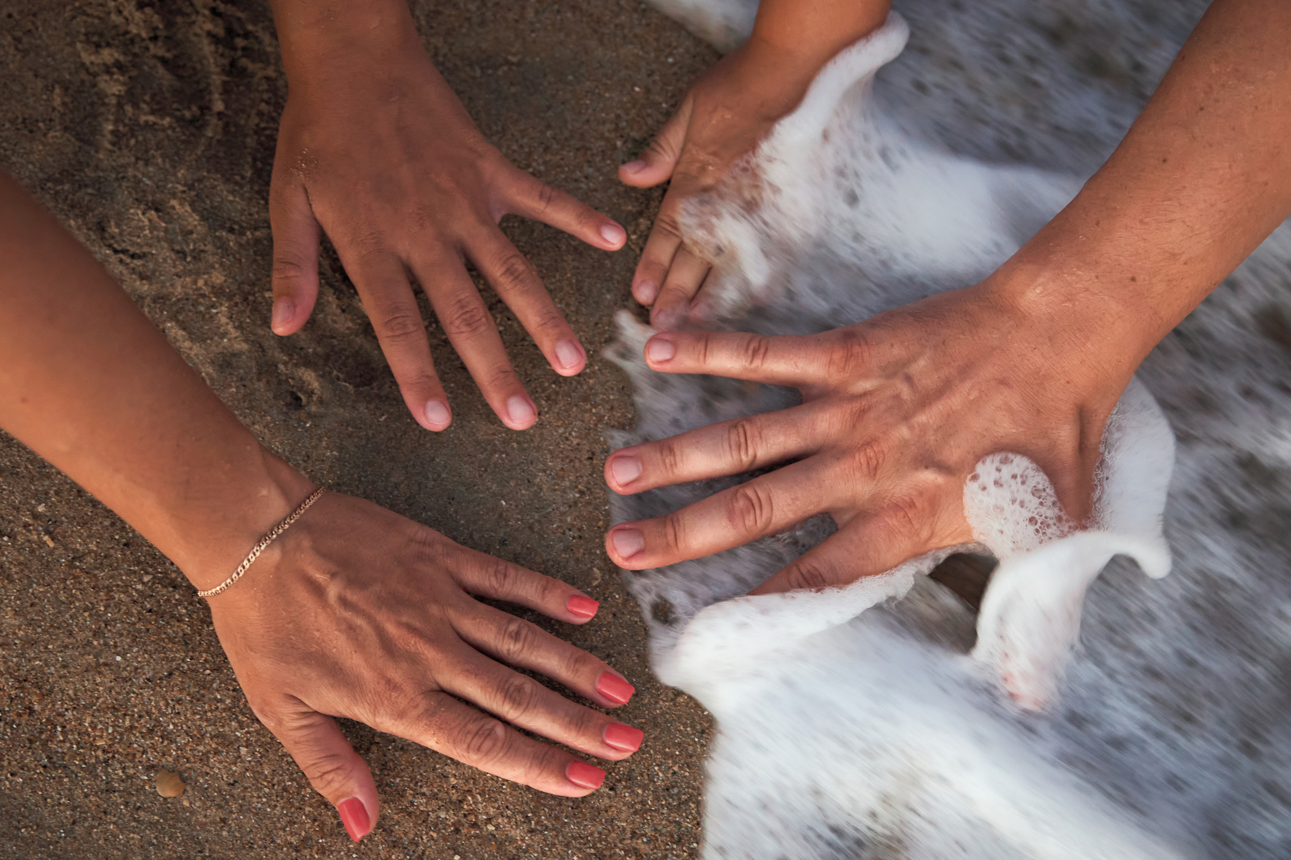 Руки родителей и детей в морской пене