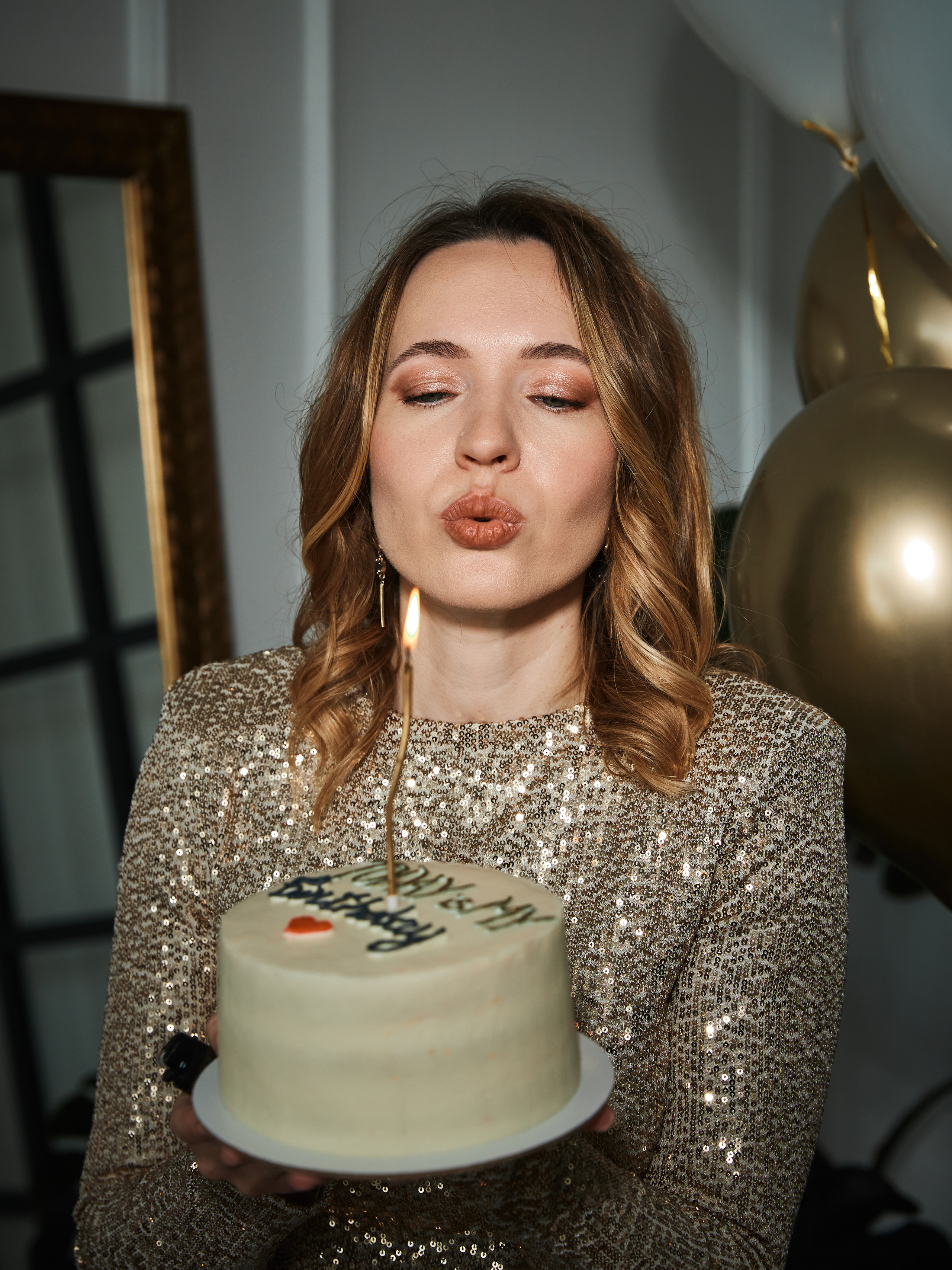 Фотосессия на день рождения, девушка задувает свечи на торте в фотостудии