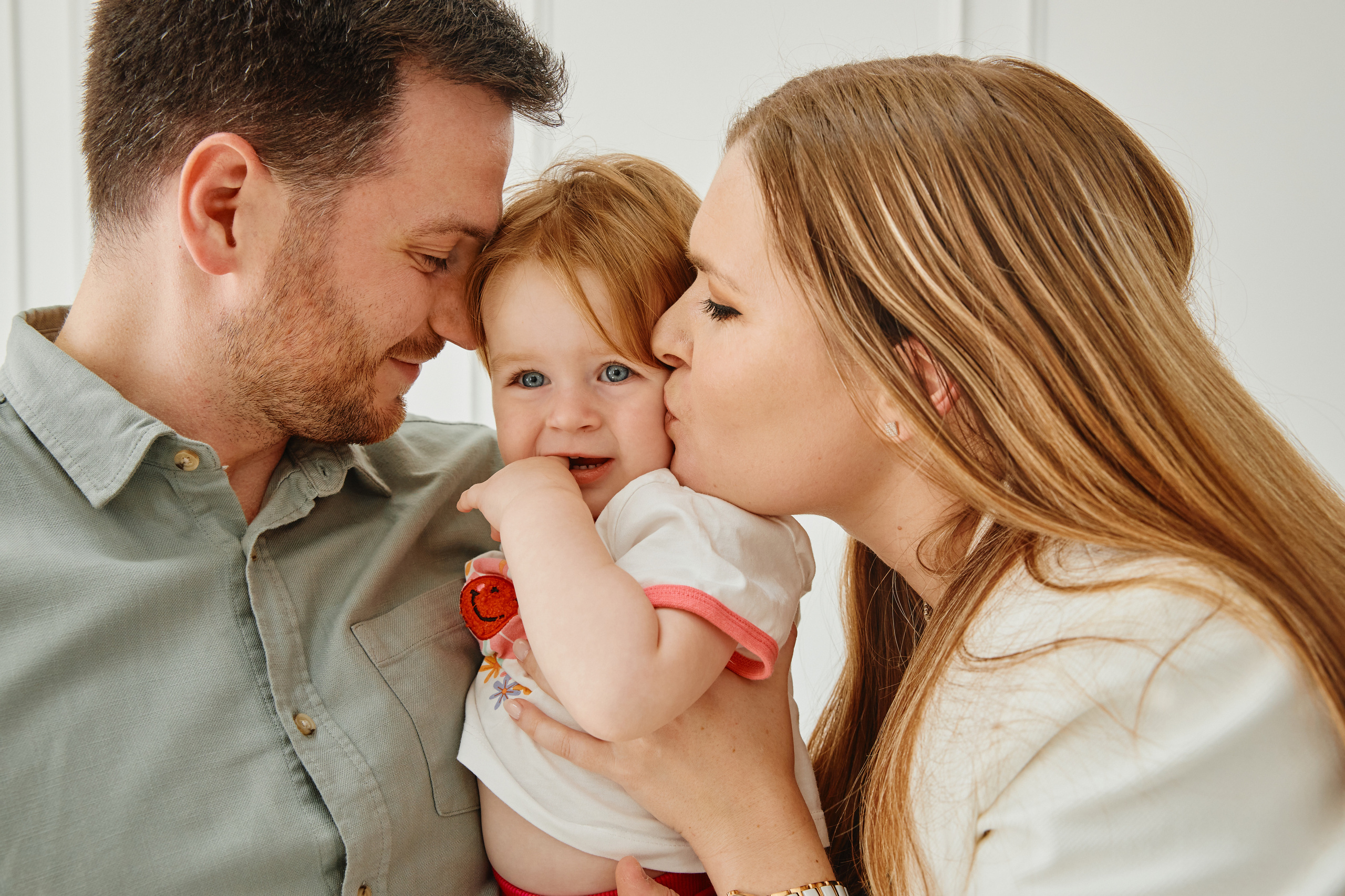 Родители целуют маленькую дочь. 