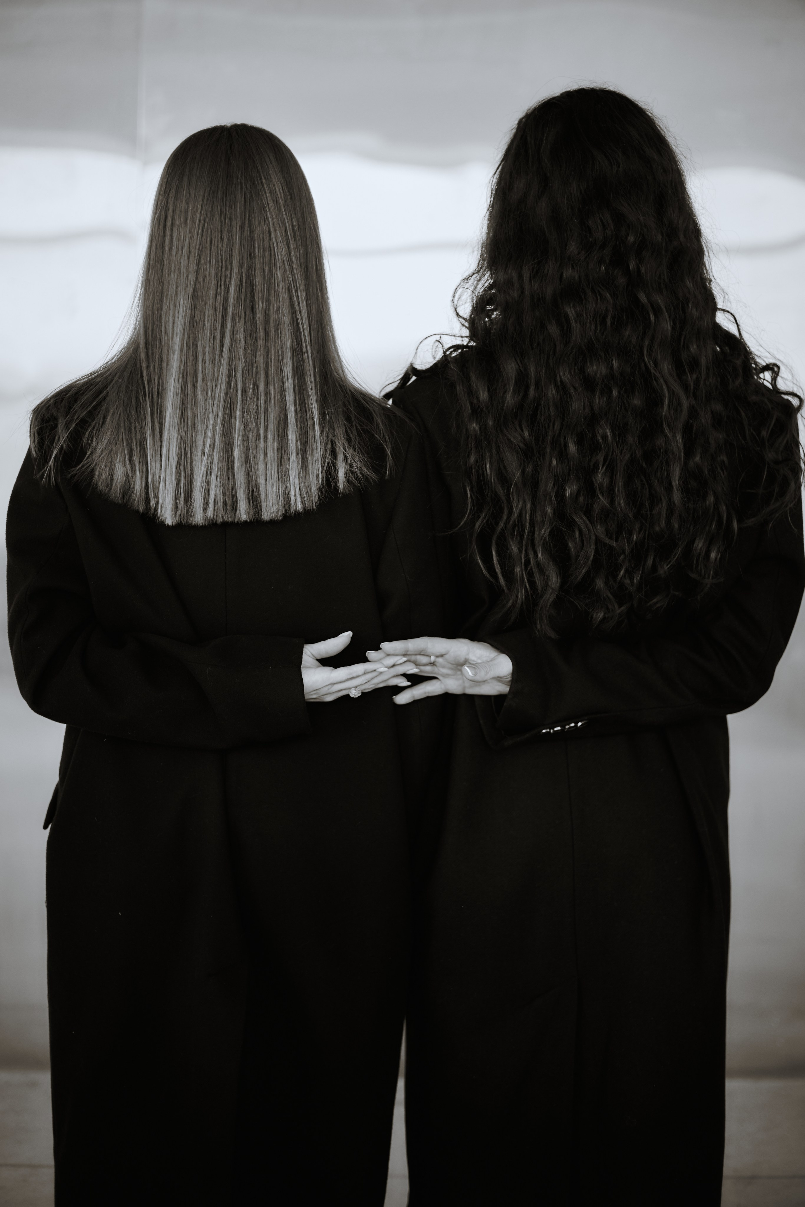 Две девушки на фоне металлической стены, стоят спиной, взявшись за руки. Виктория Брызгалова и Анна Пижонкова