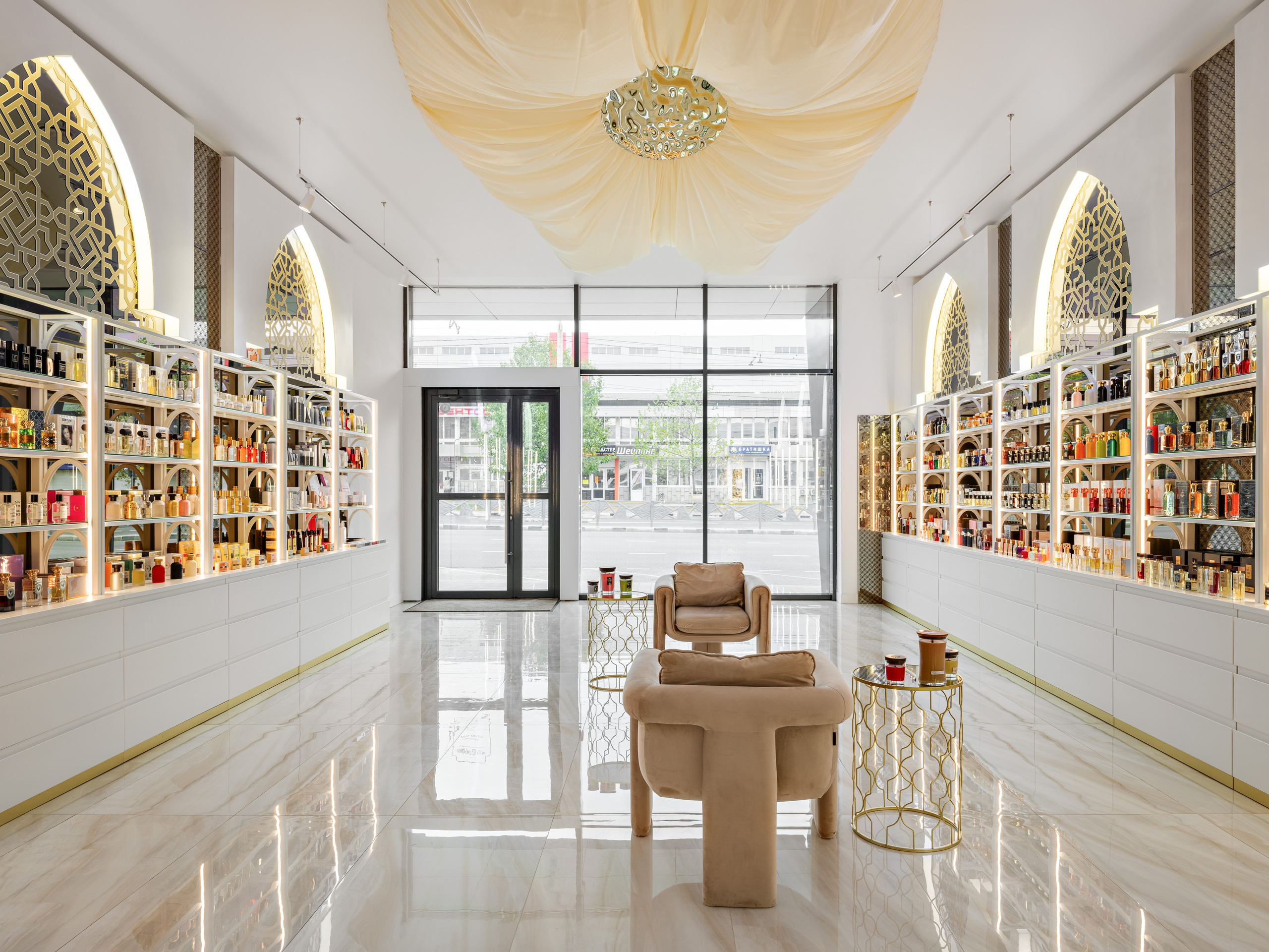 Вид на входную зону парфюмерного бутика с панорамными окнами, белыми витринами и золотыми восточными арками. Современный интерьер luxury-класса, дизайнер Мария Никишина, фотограф Сергей Денисенко.