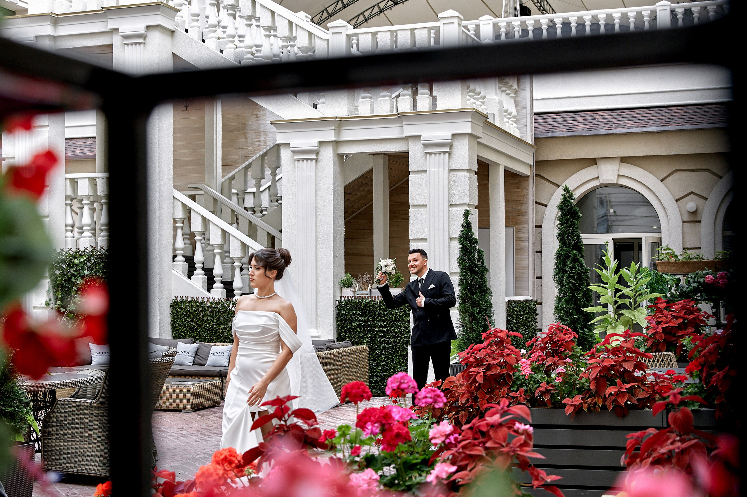 Жених Тальгат с букетом показывает класс, невеста Наиля идет рядом. Свадебная фотосессия через рамку с красными цветами. Фотограф Орешина Елена — лучший фотограф Ульяновска.