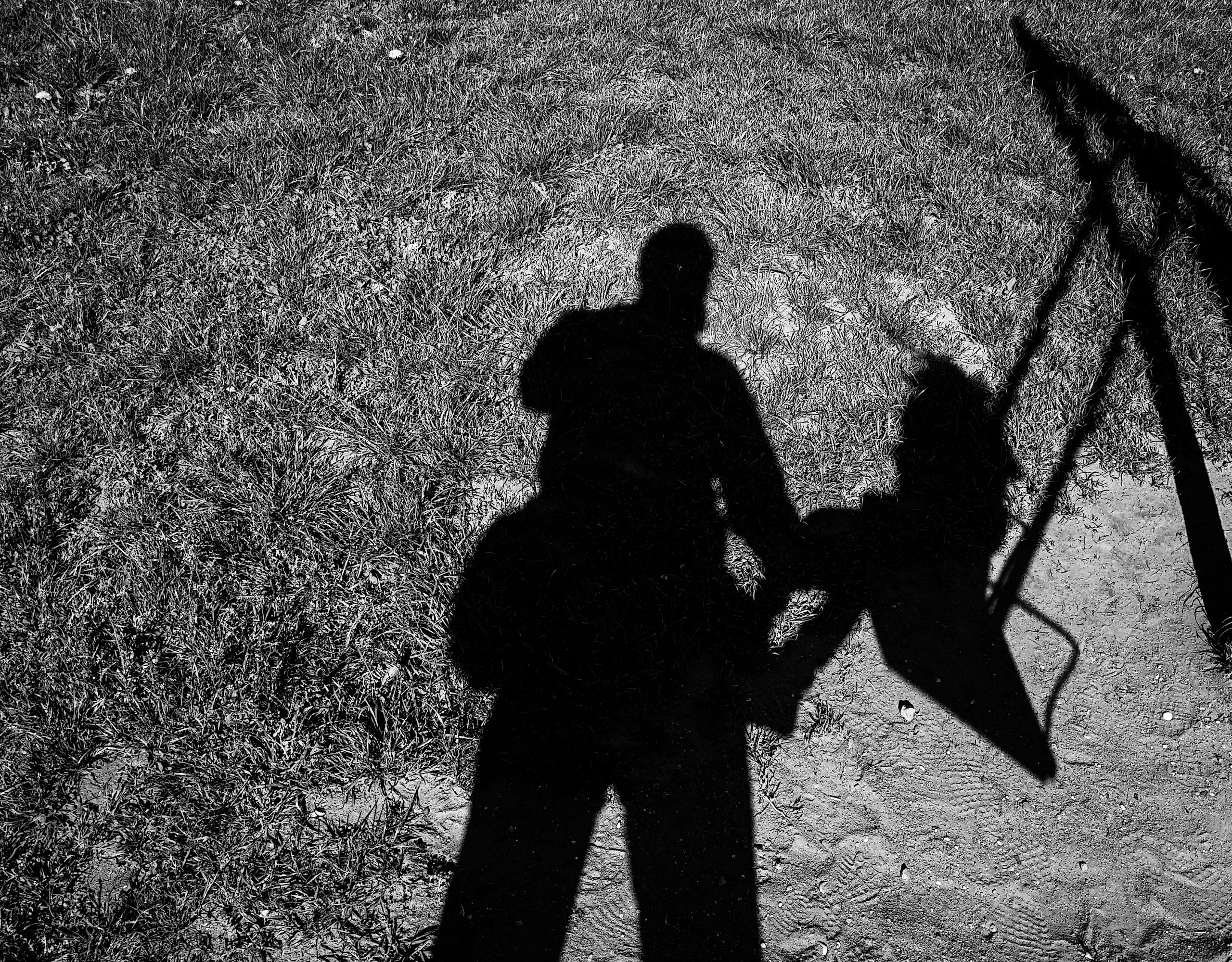 тень мужчины и девочки на качелях