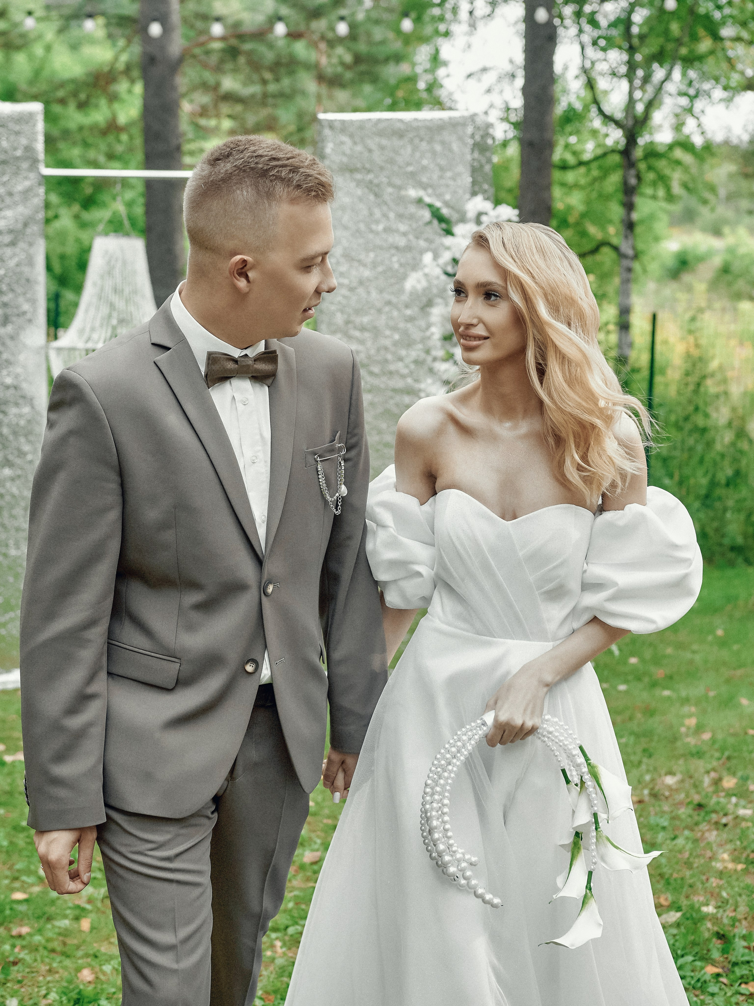 «Свадебная пара идёт за руки у арки, выездная регистрация в лесу, фотосессия в экохаусе»