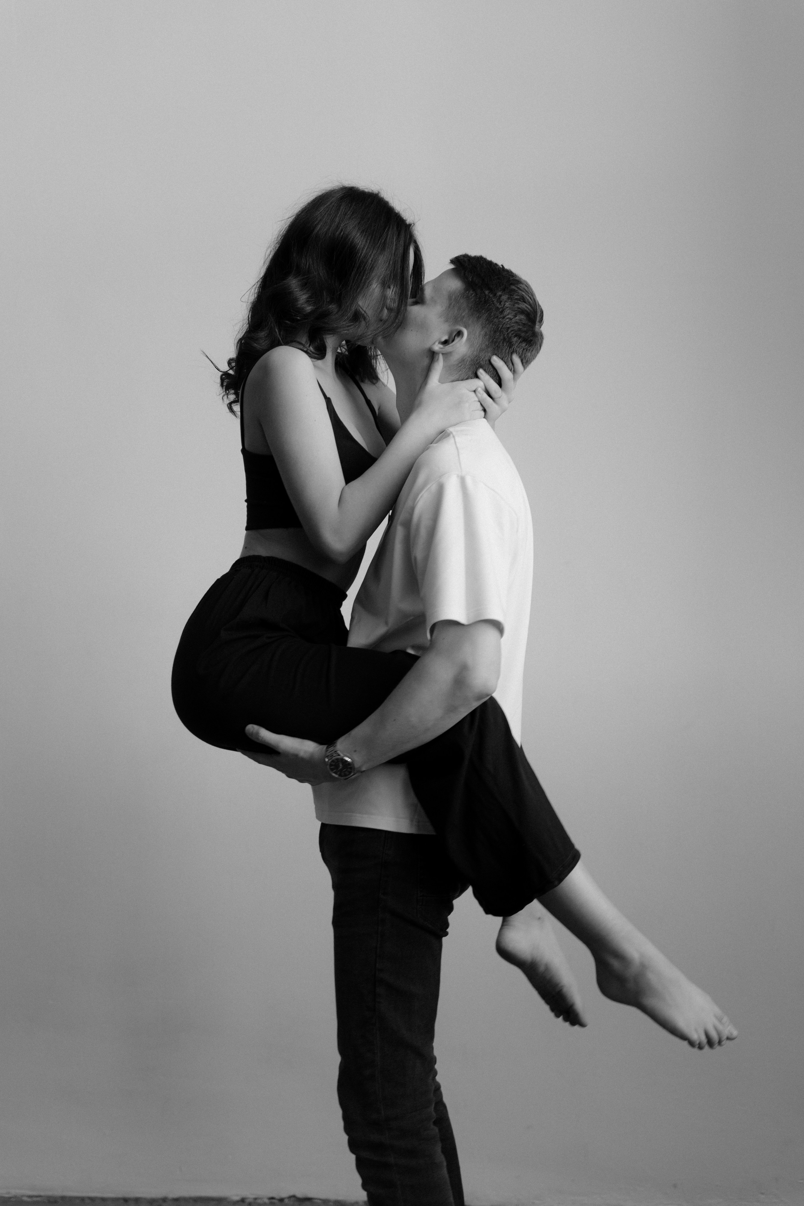 Девушка запрыгнула на парня спереди и целует его и смеется