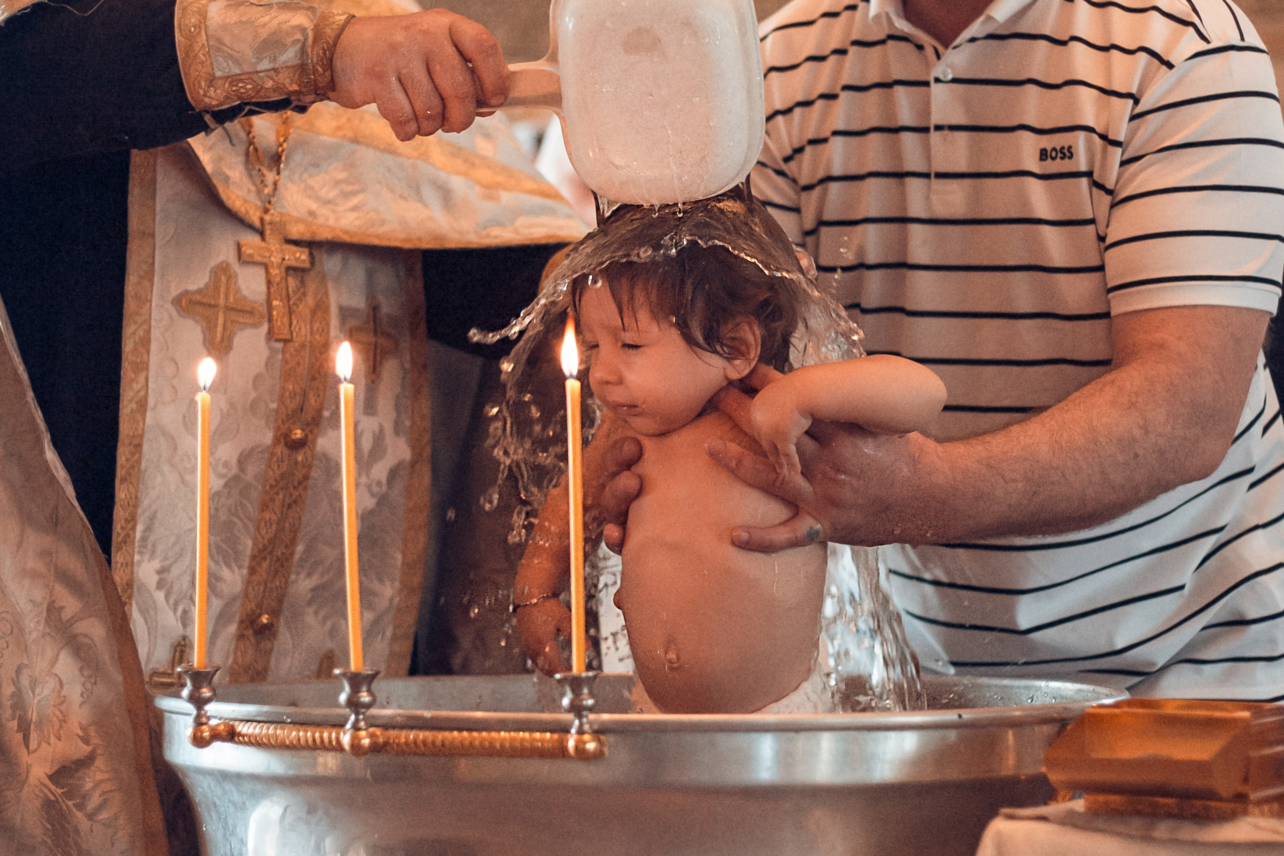 Малыш в купели во время таинства крещения