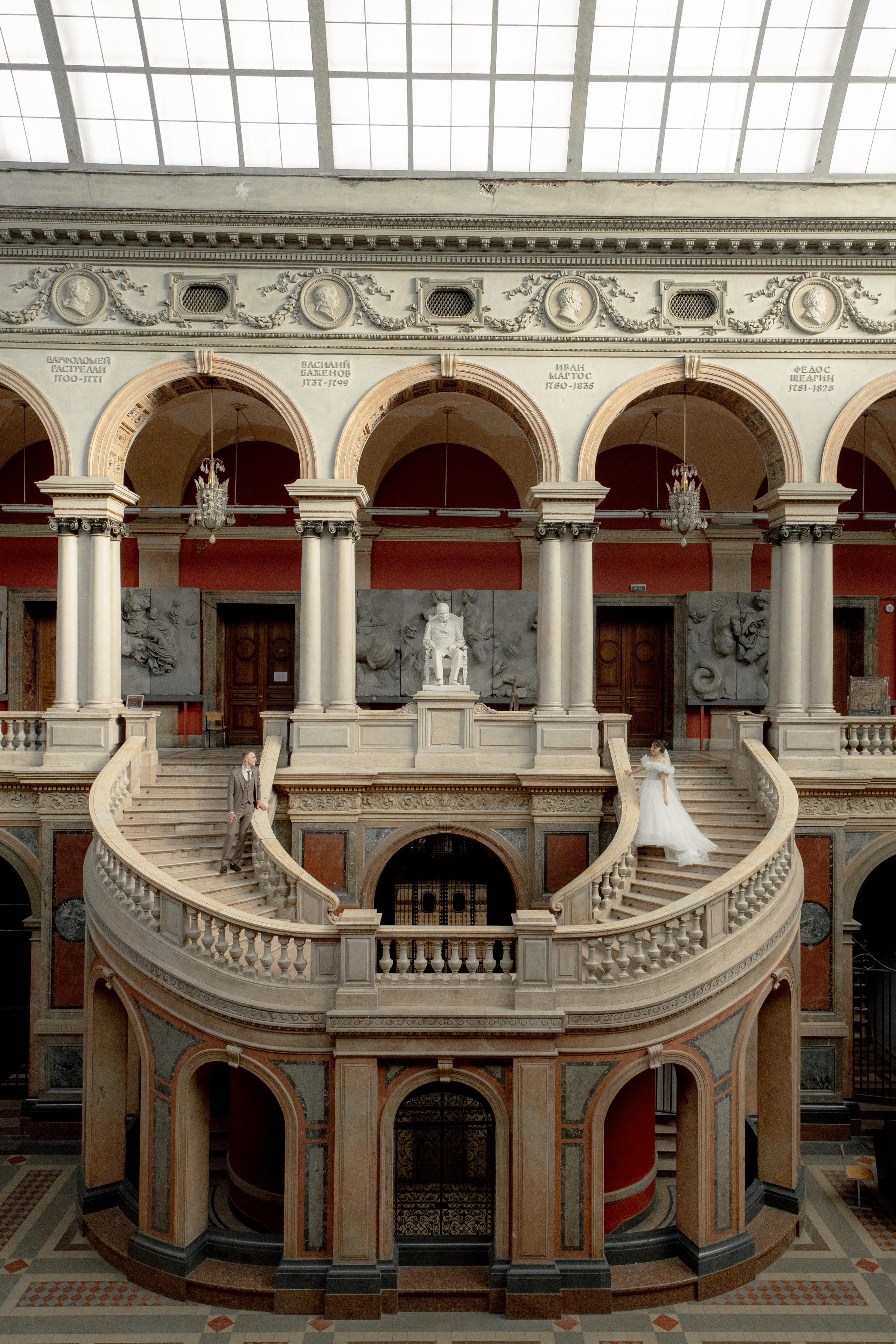 парадная лестница в академии Штиглица и свадебная пара стоит по краям