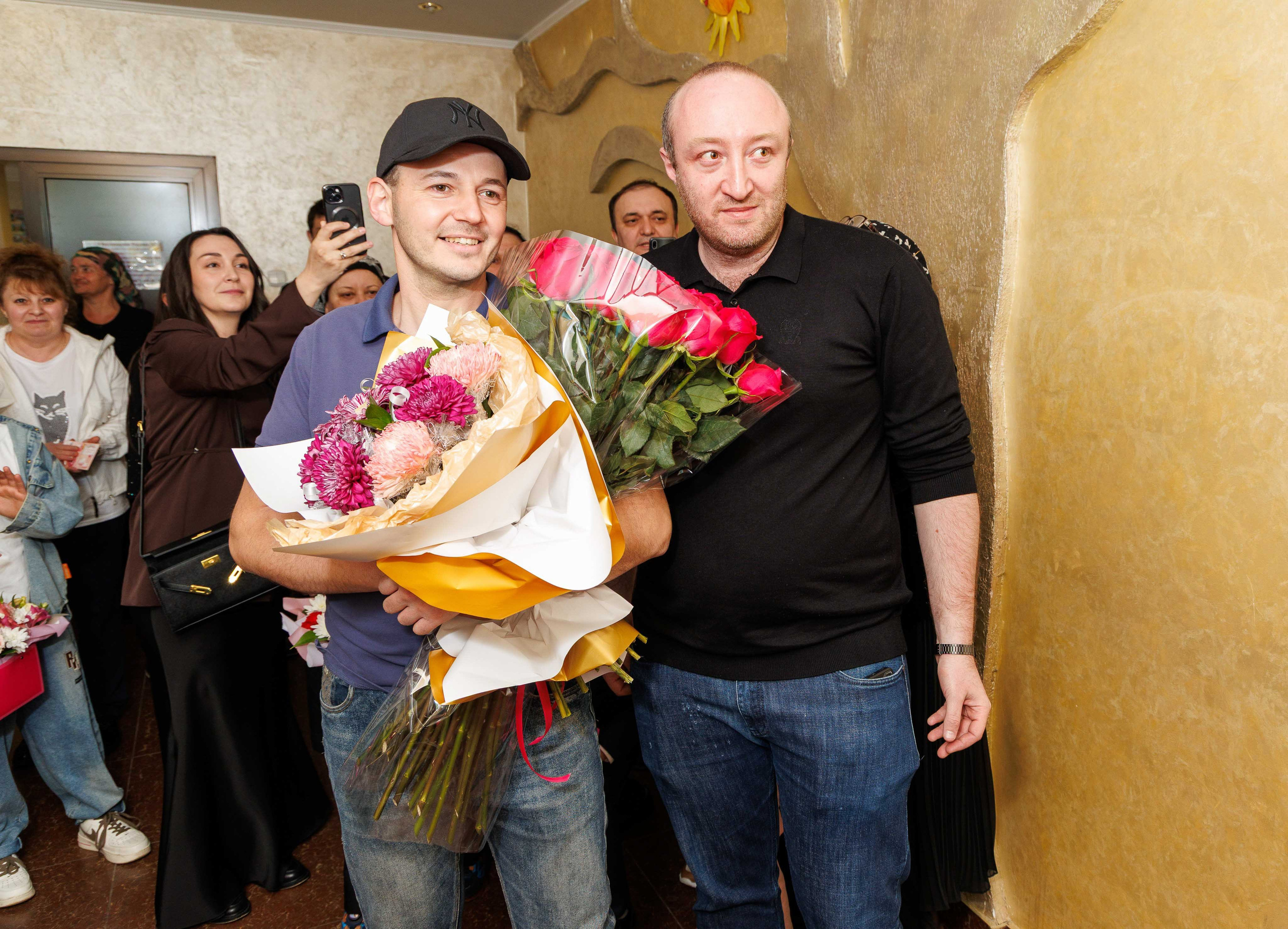 Счастливый папа вручает огромный букет цветов маме при выписке.