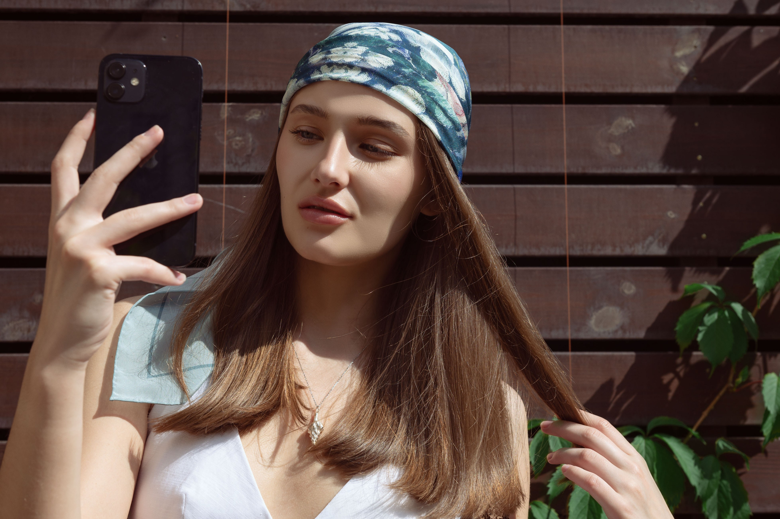 Красивая девушка в дизайнерской бандане делает сэлфи