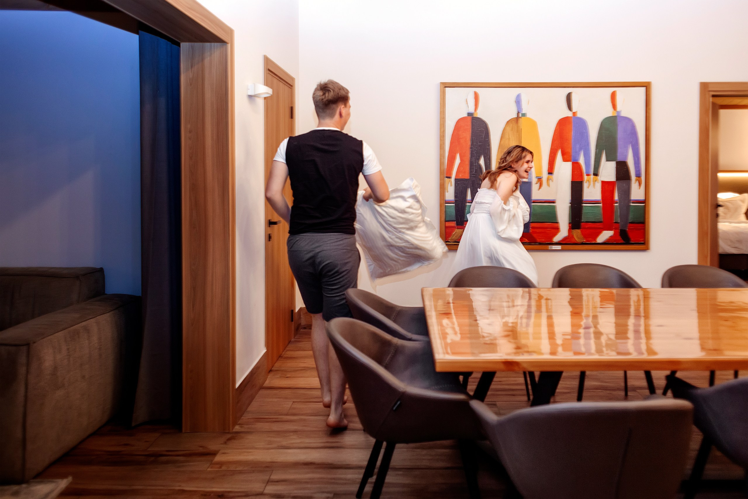 Парень с девушкой дерутся подушками внутри комнаты